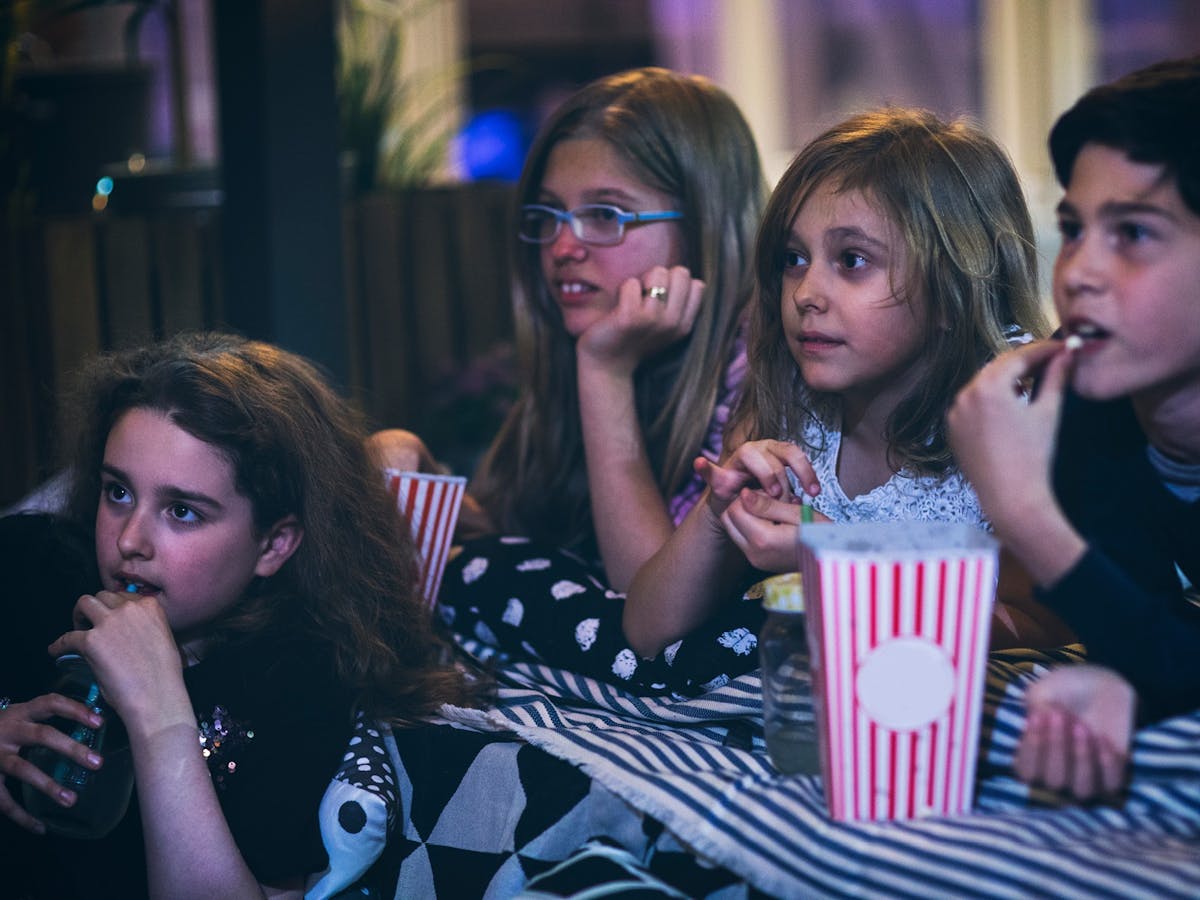Children watching a movie and eating popcorn