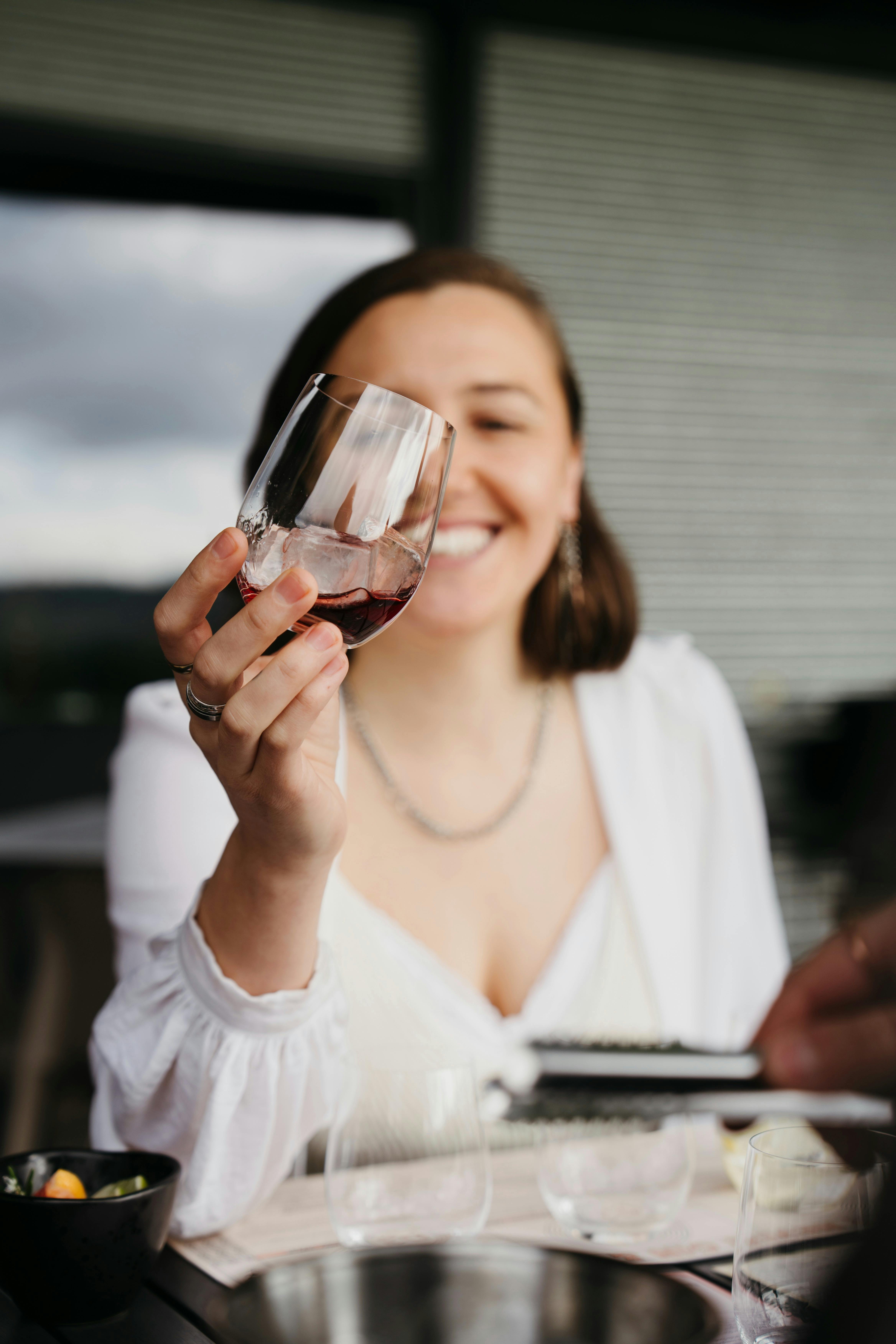 Woman enjoying a drink from a tasting glass at a table