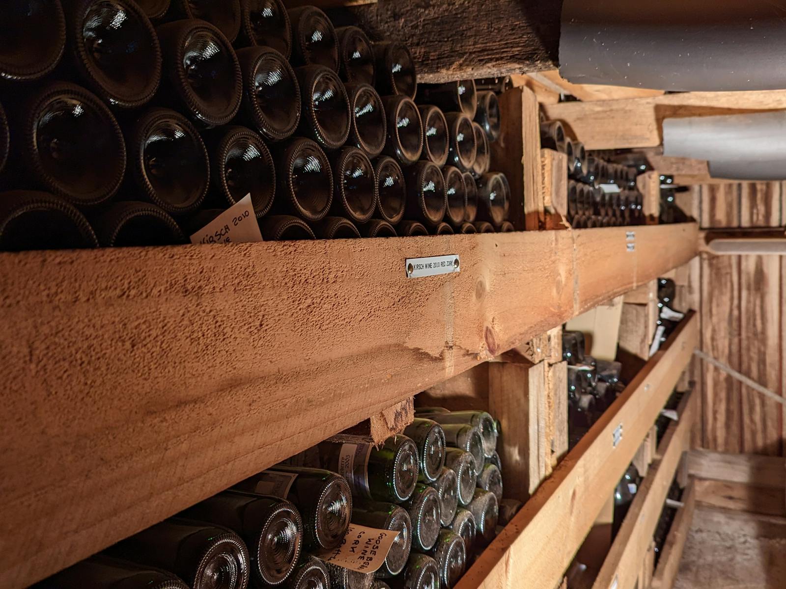 dusty bottles of wine on wooden shelving in cellar