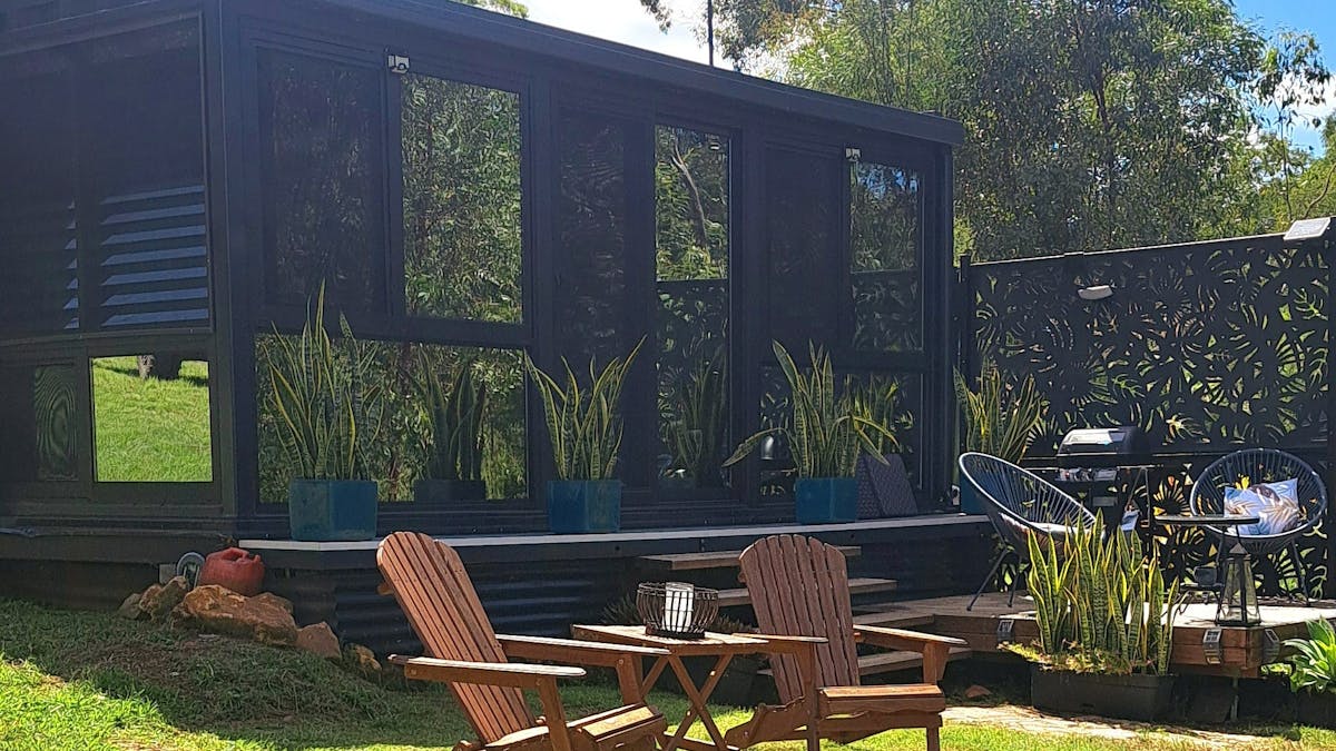 a image of a container conversion tiny home set amongst the trees. With firepit and seating a image of a container conversion tiny home set amongst the trees. With firepit and seating