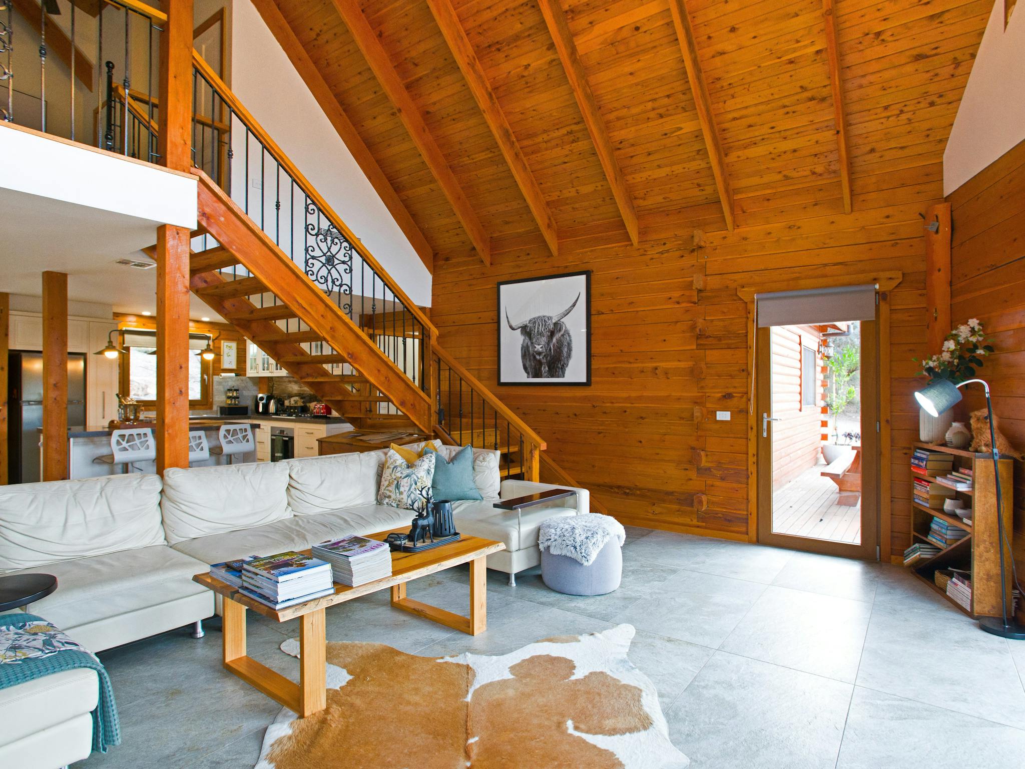 Living room with timber ceilings, bookcase, and large sectional lounge