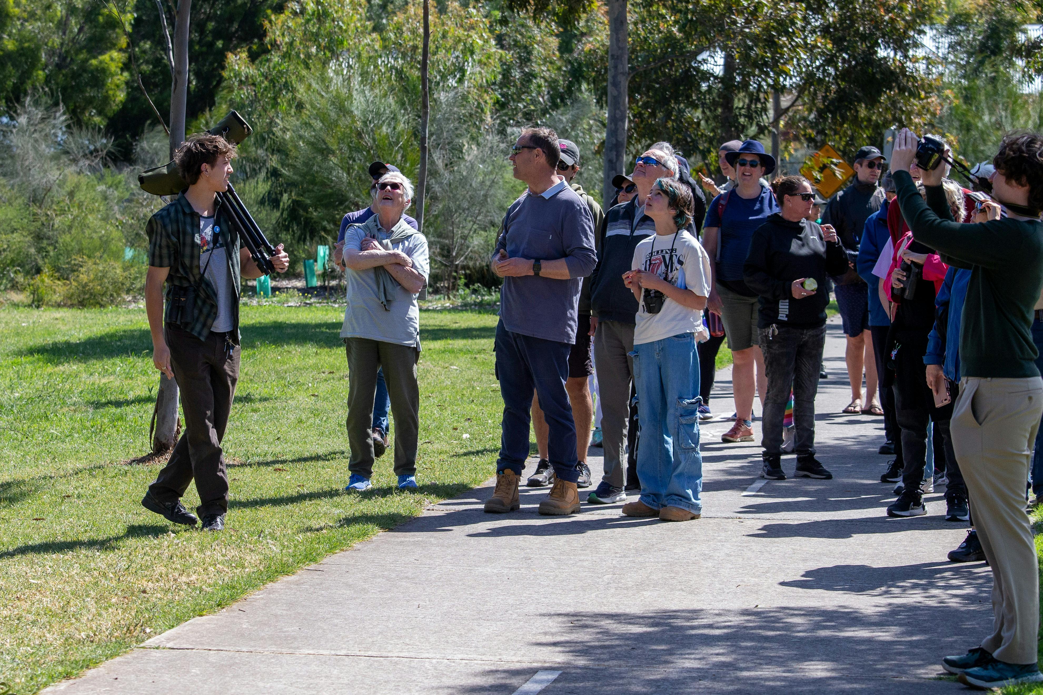 Group of people being led on a bird walk by man with scope.