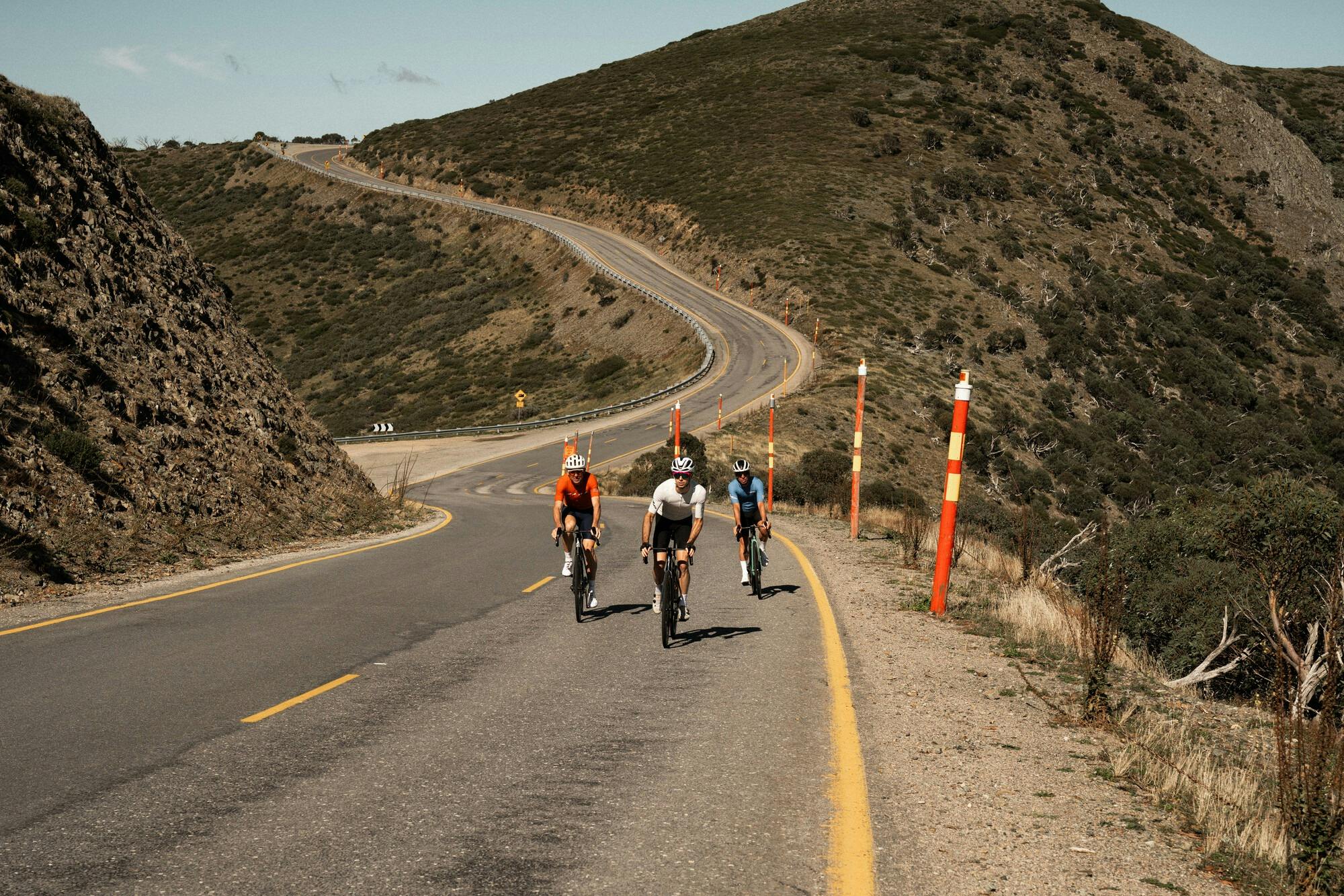Three cyclists riding past mountain views on the Mt Hotham 7 Peaks Challenge route