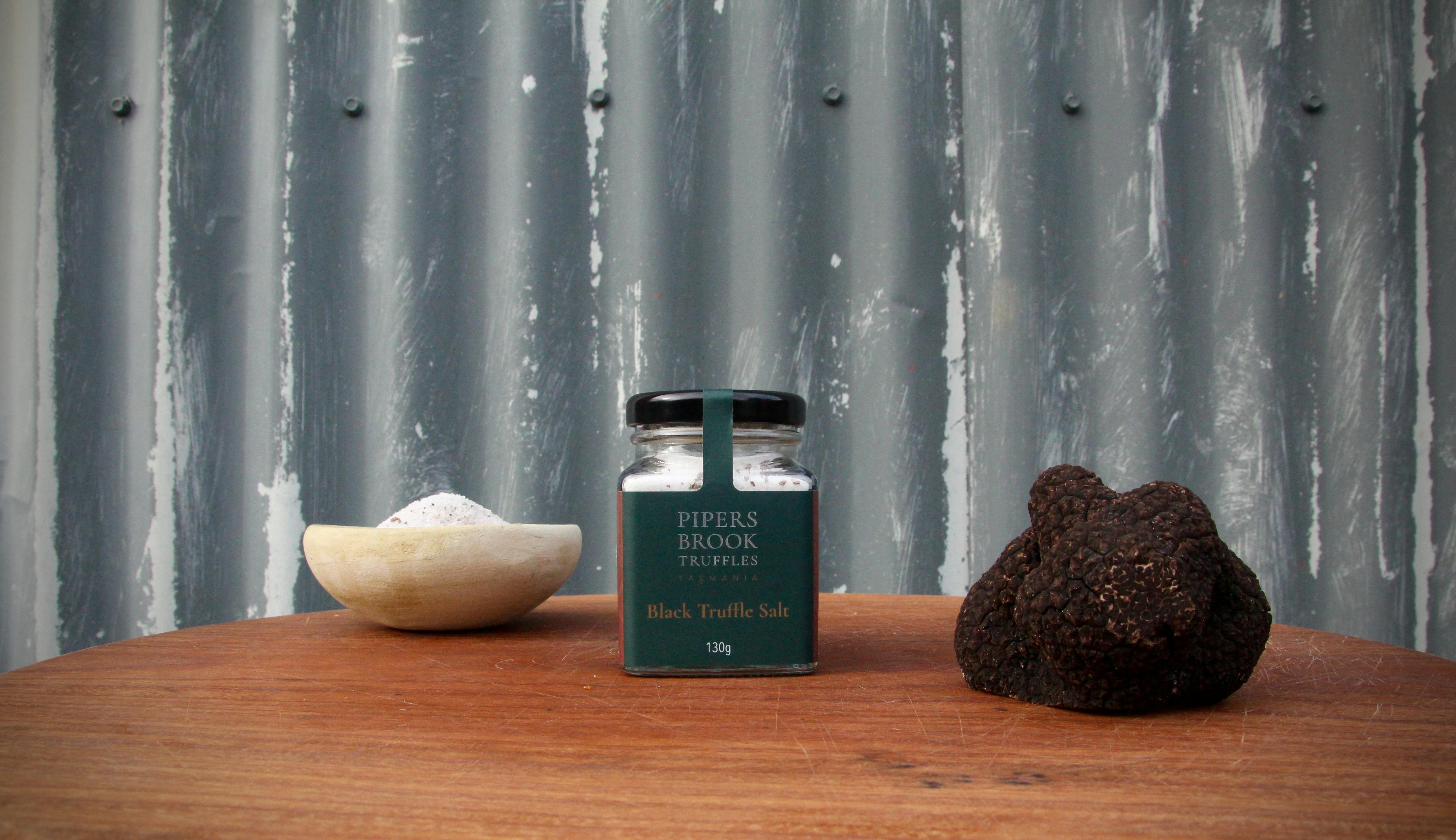 Jar of truffle salt with fresh black truffle and salt in a dish in the background