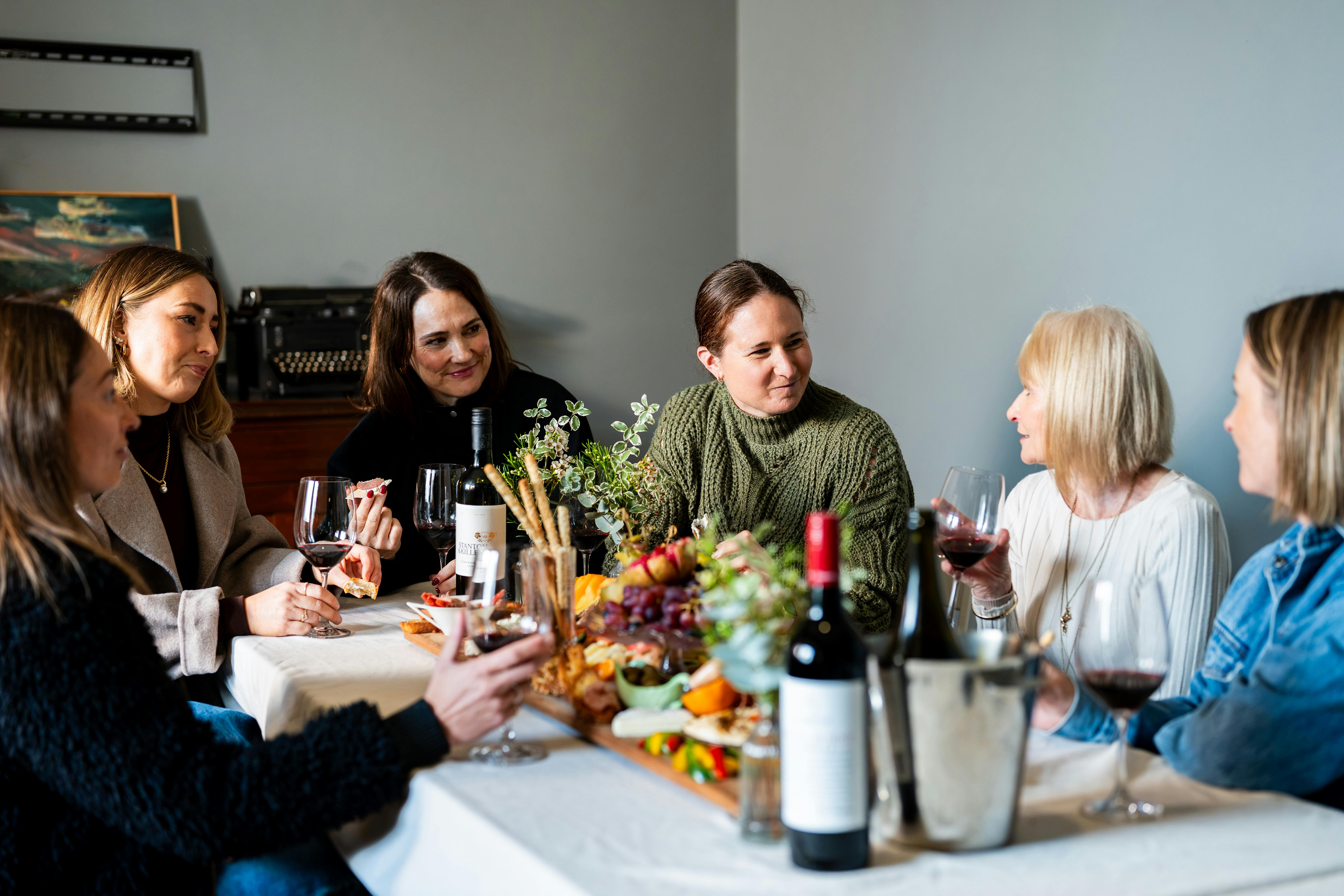 Four women eating and drinking wine in the gallery room