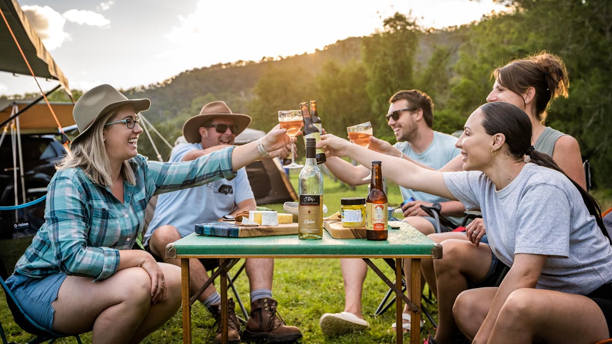 Friends sitting around a camping table with cheese, wine and beer at Kerry Valley Secret.