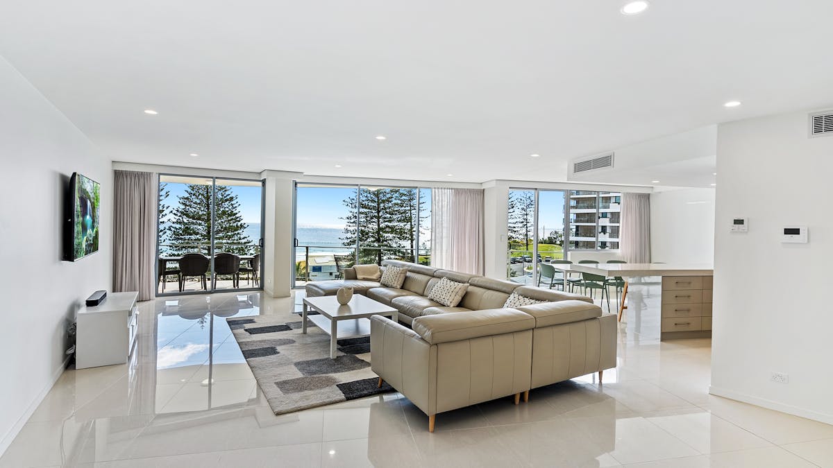 Stylish lounge featuring a leather chaise lounge, high-gloss tiled floors, and stunning ocean views