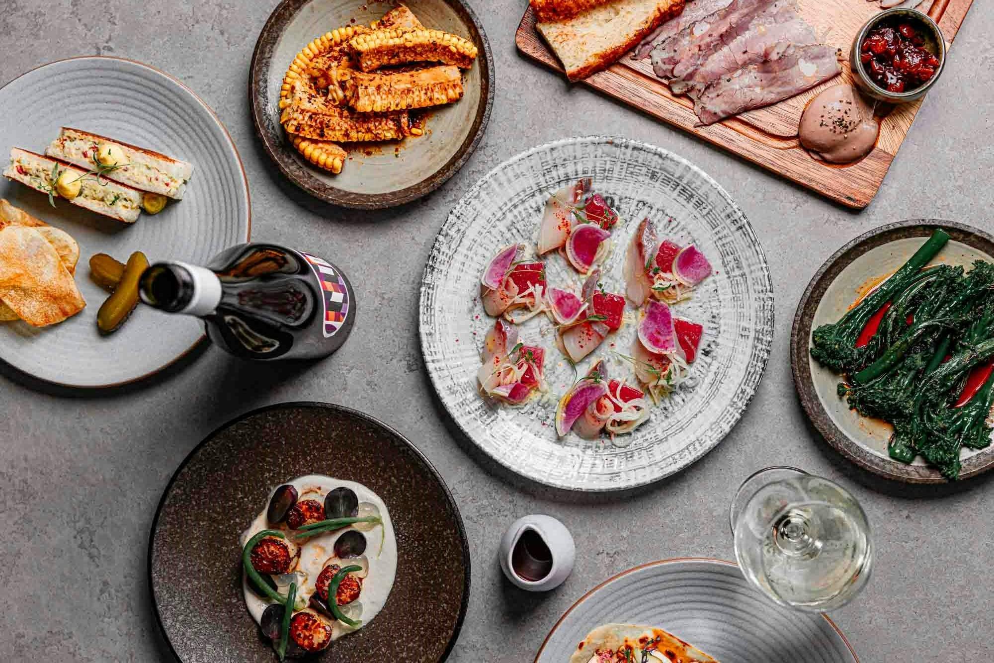 A table spread of plates at Gather - seafood, steaks, sides and more.