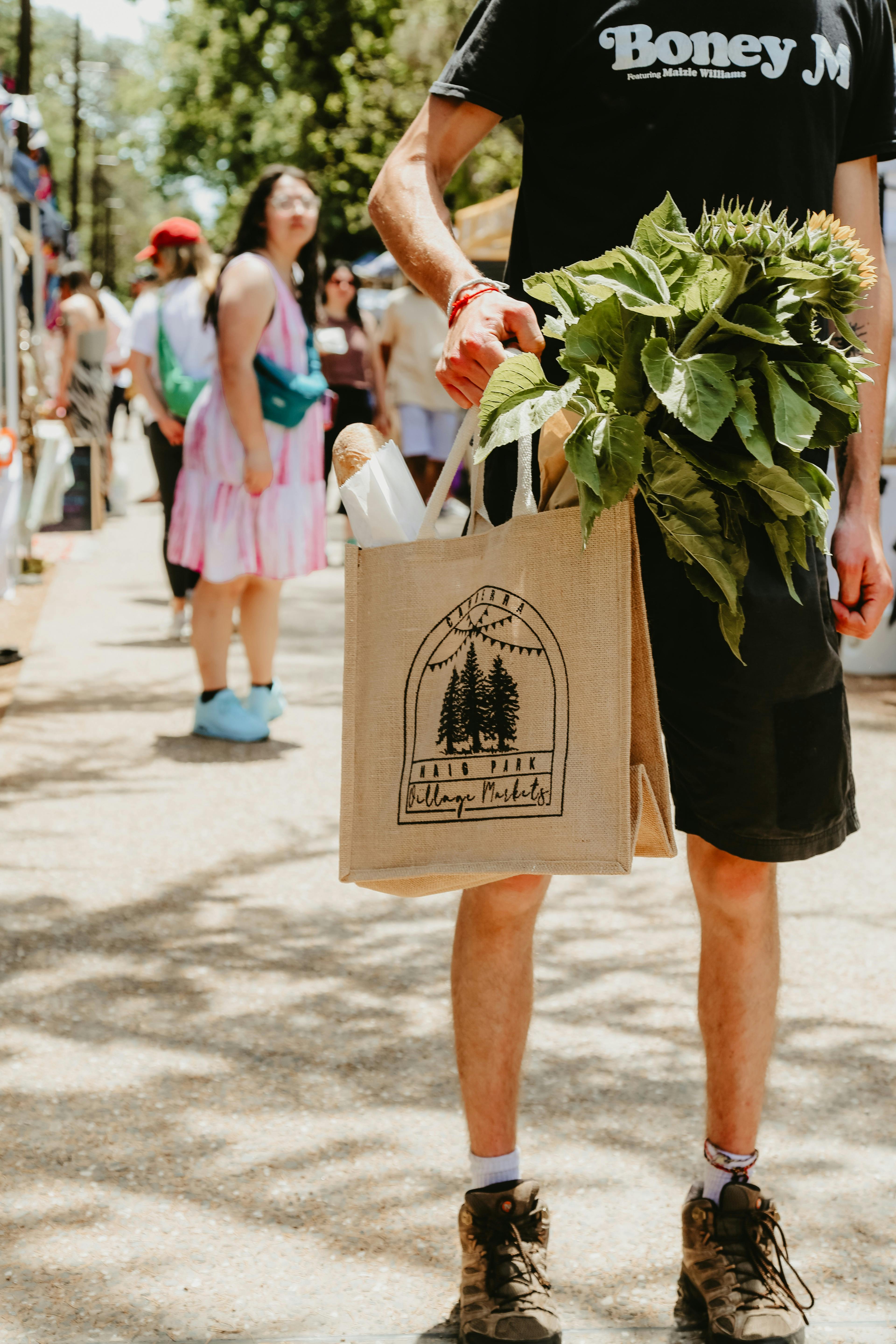 A peson holding a hessian Haig Park Village Market bag filled with bread and produce
