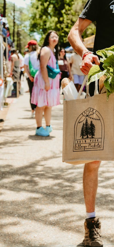 A peson holding a hessian Haig Park Village Market bag filled with bread and produce