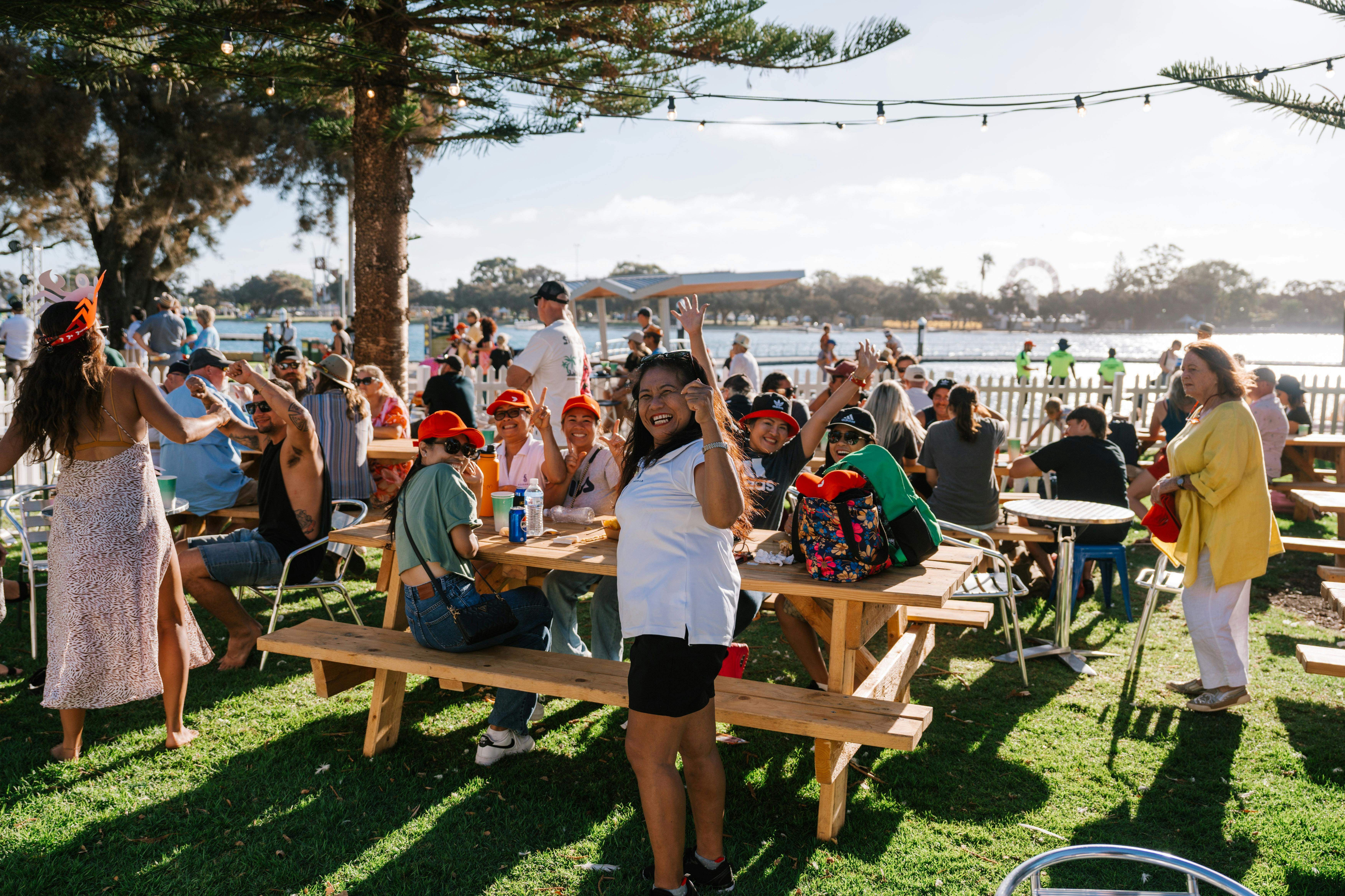 Crowd of people under trees sitting and enjoying food at crab fest