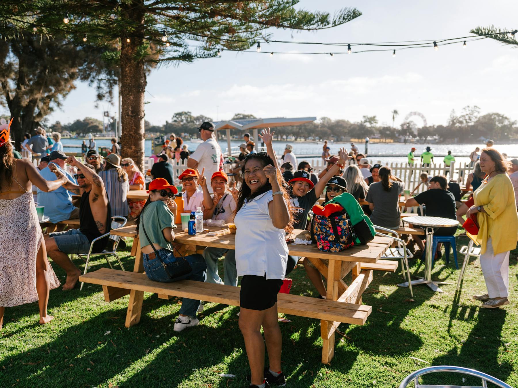 Crowd of people under trees sitting and enjoying food at crab fest