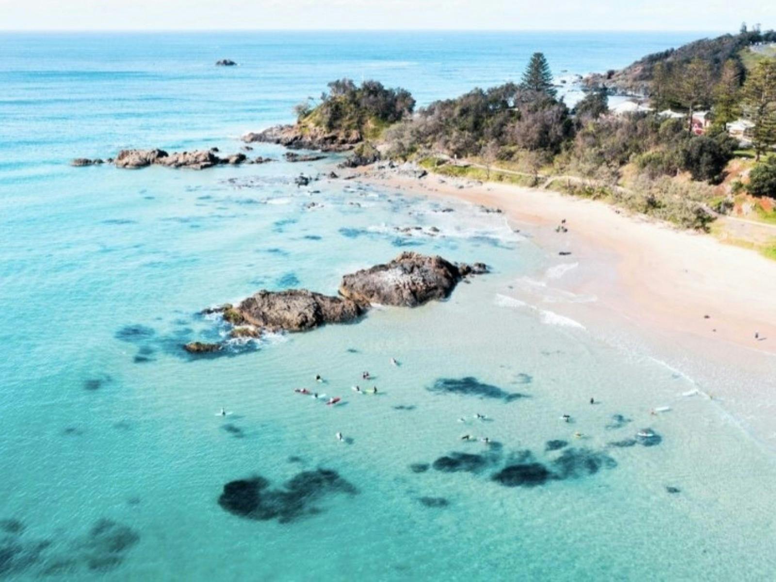 Sandy beach with gentle waves and a clear blue sky.