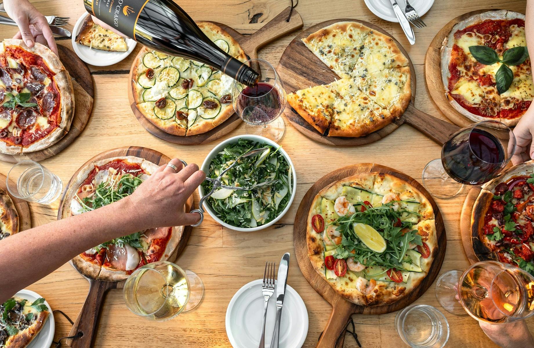 Gourmet pizza served on a table with glasses of wine