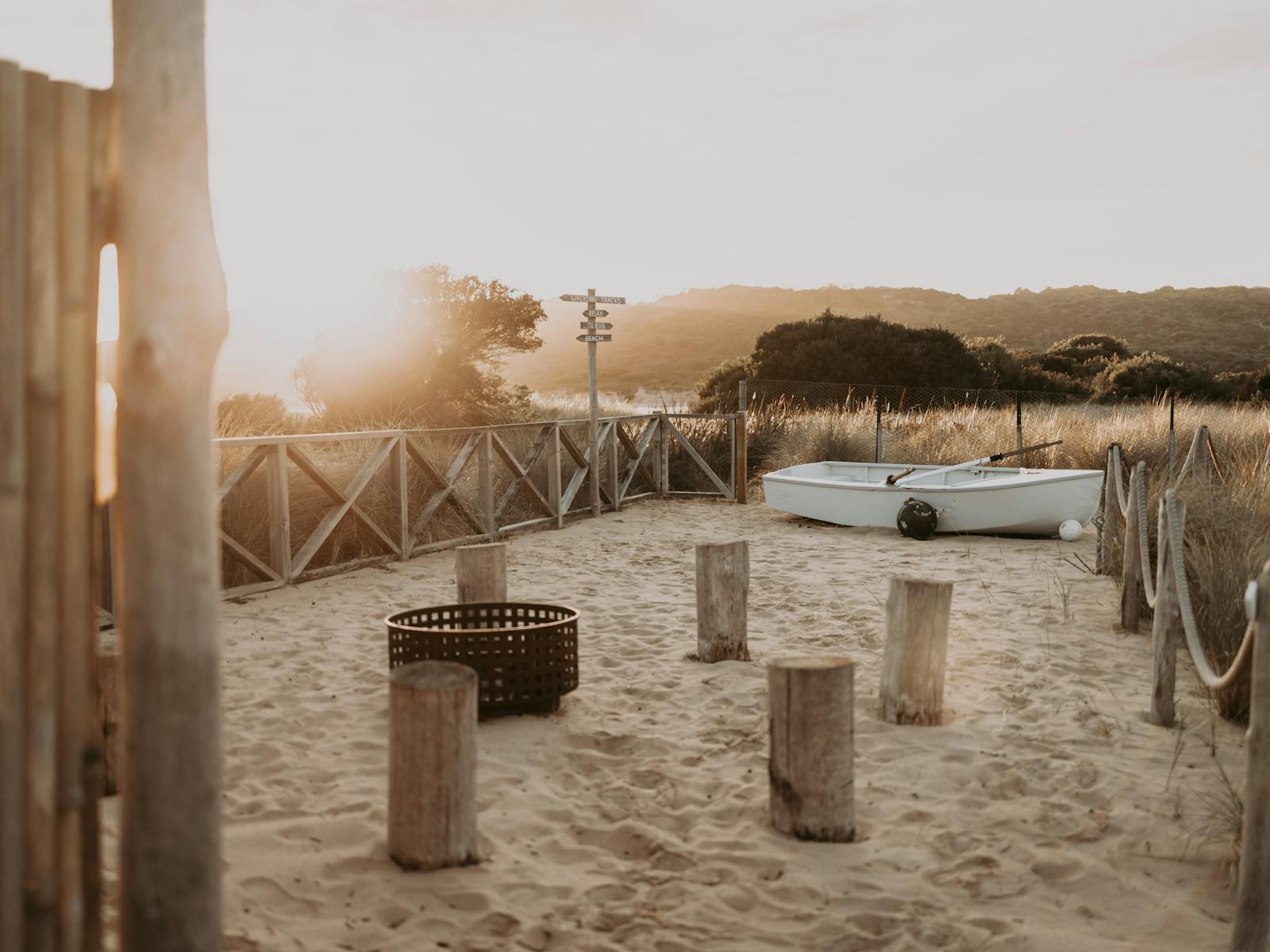 An outdoor beach area with seating and firepit at sunset