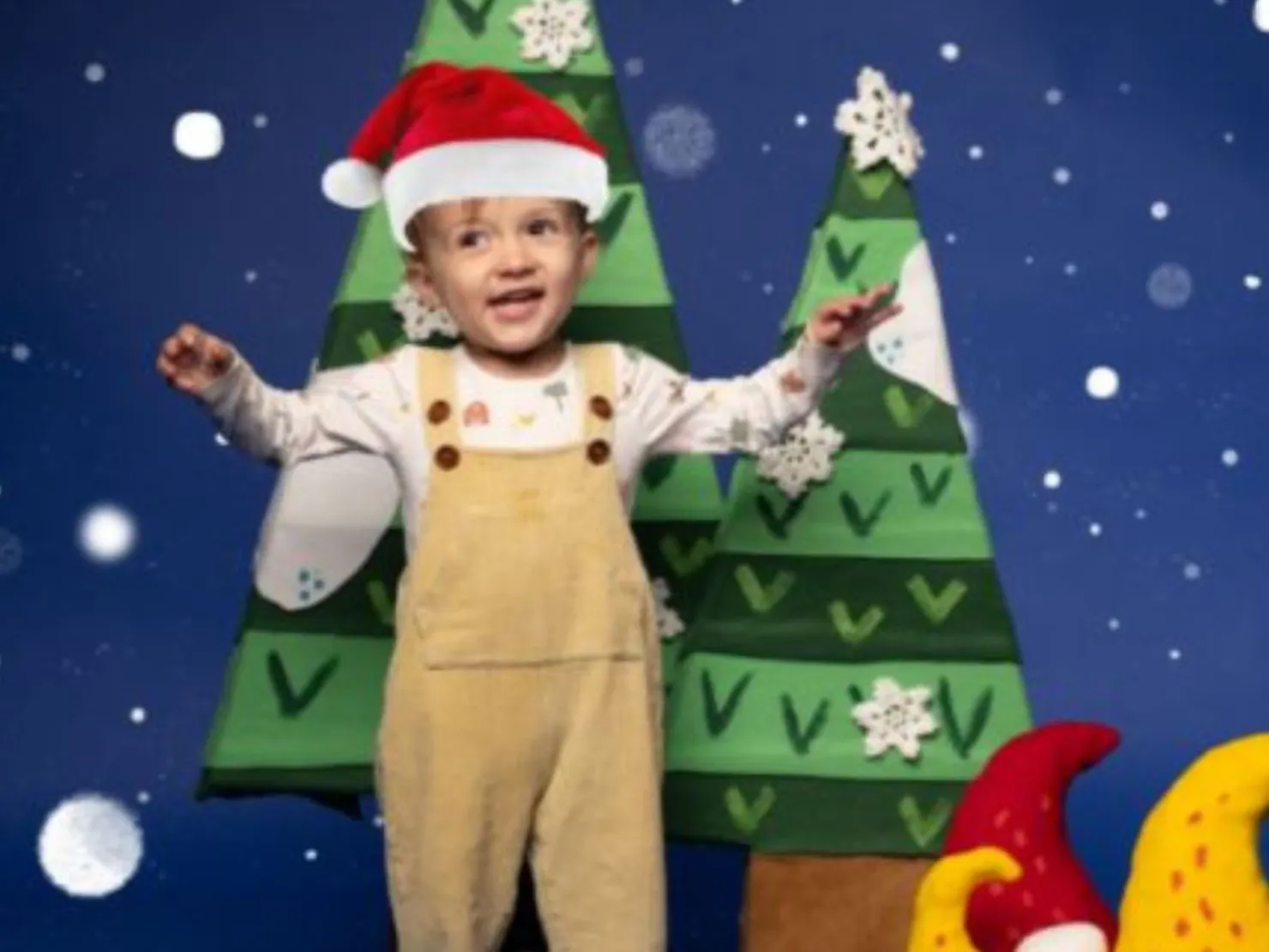 little child in bone overalls with christmas hat on