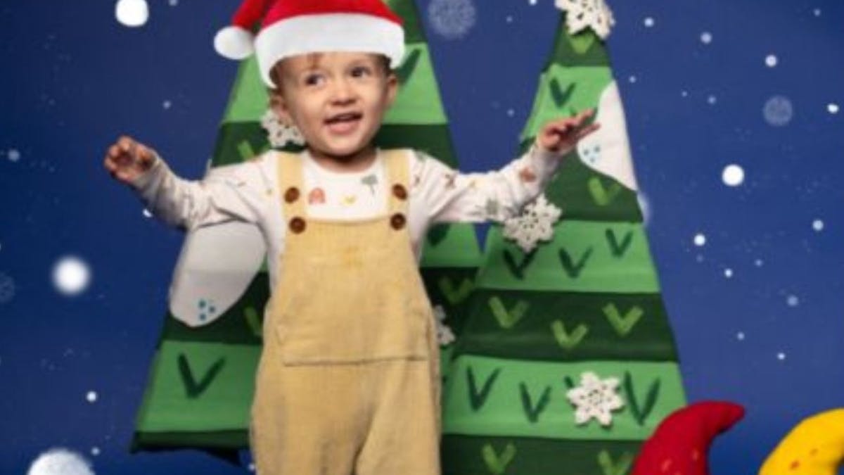 little child in bone overalls with christmas hat on