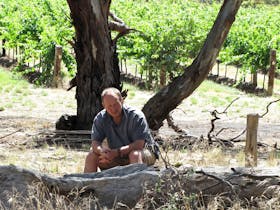 Man seated in front of gum trees and vines