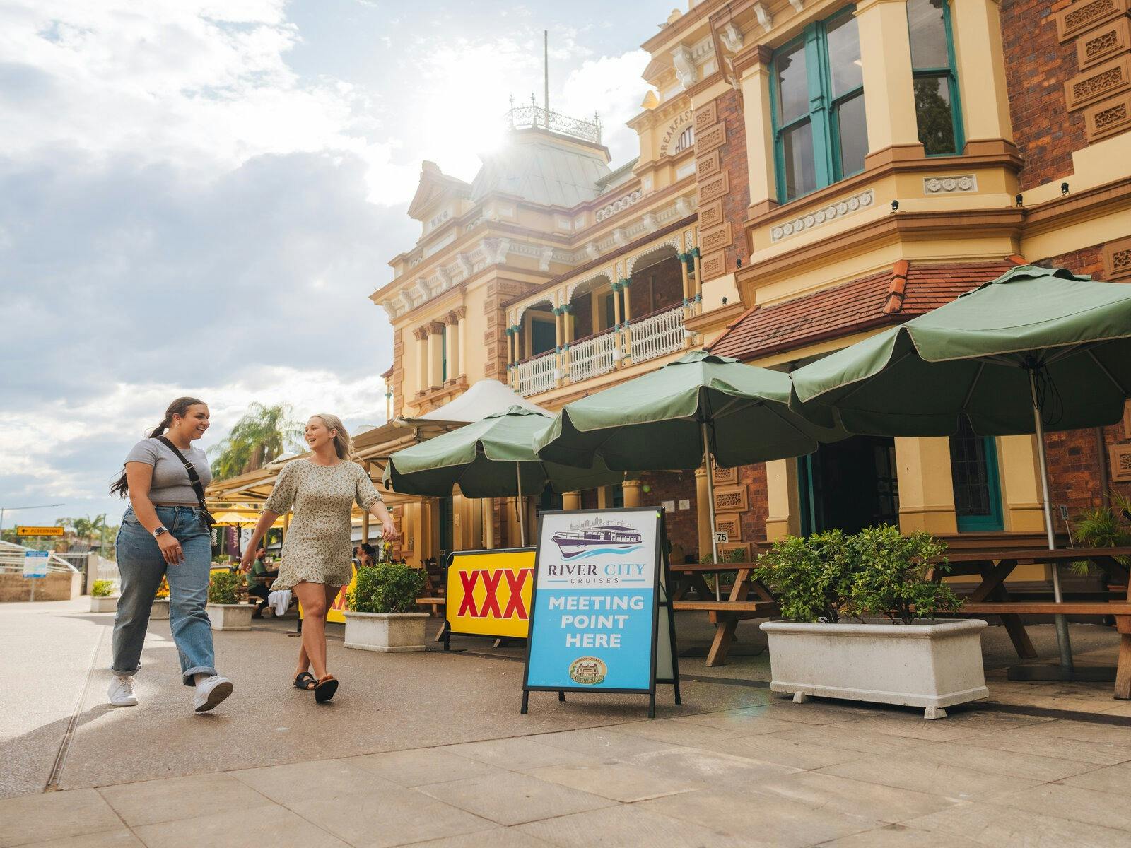 Two people walking in front of the Breakfast Creek Hotel