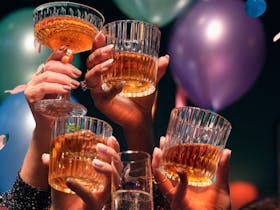 A group of people enjoying celebrating New Years Eve. They are, holding their glasses up in the air.