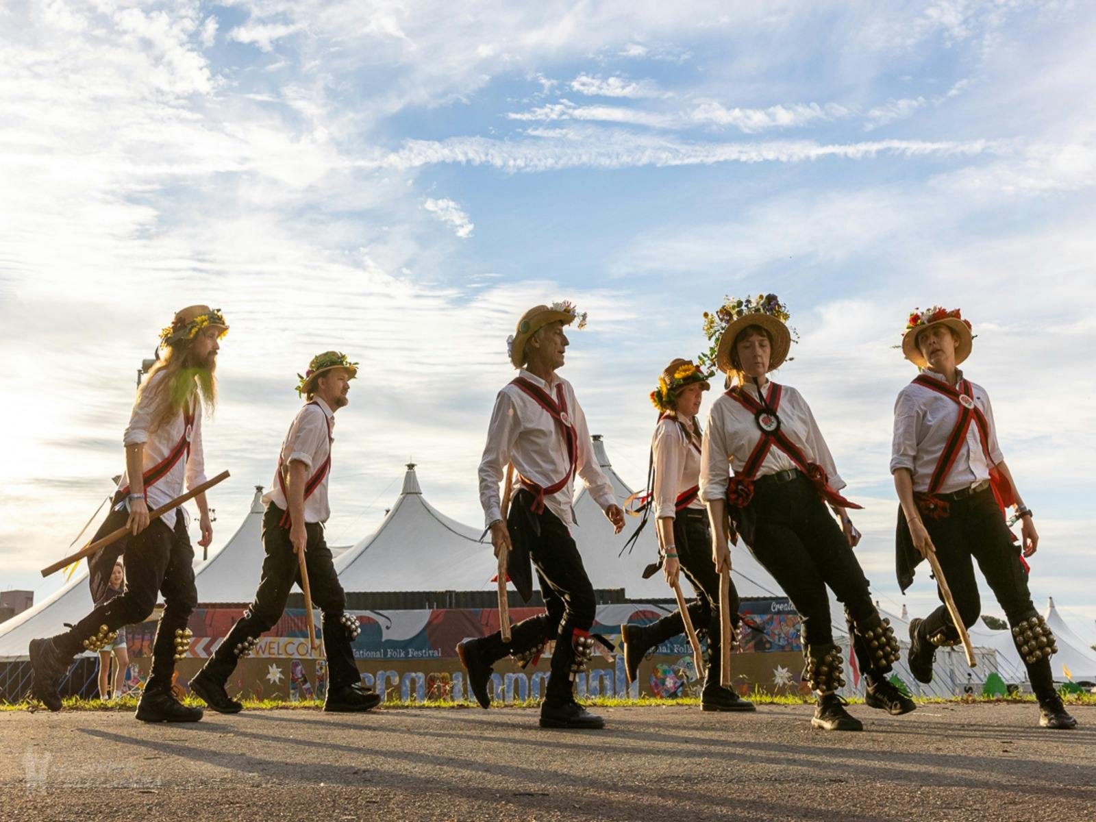 6 Morris Dancers perform in Traditional Costume with a big-top tent in the background