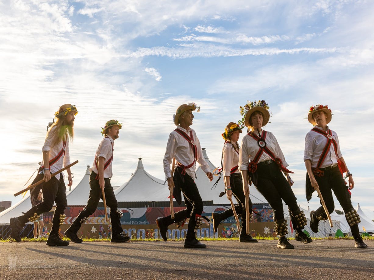 6 Morris Dancers perform in Traditional Costume with a big-top tent in the background