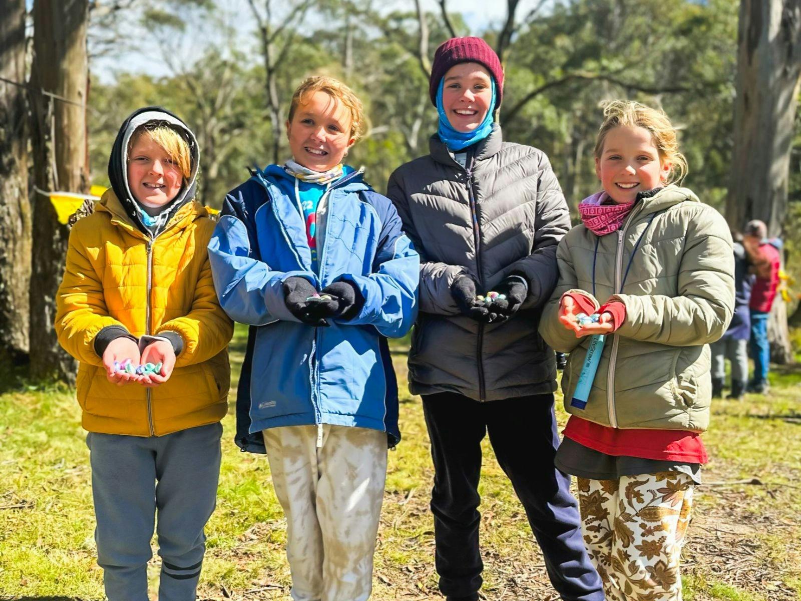 Four kids smiling at the camera as they show off the Easter eggs they found