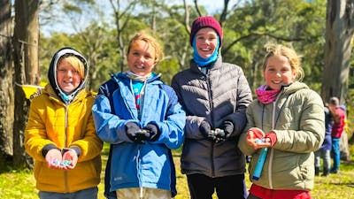 Four kids smiling at the camera as they show off the Easter eggs they found