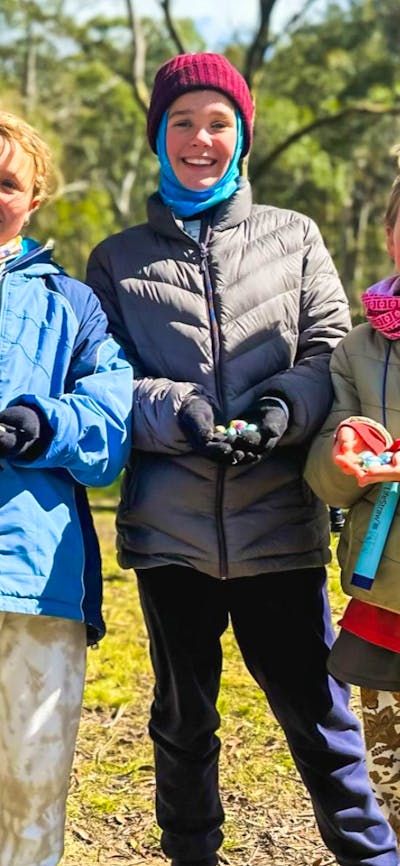 Four kids smiling at the camera as they show off the Easter eggs they found