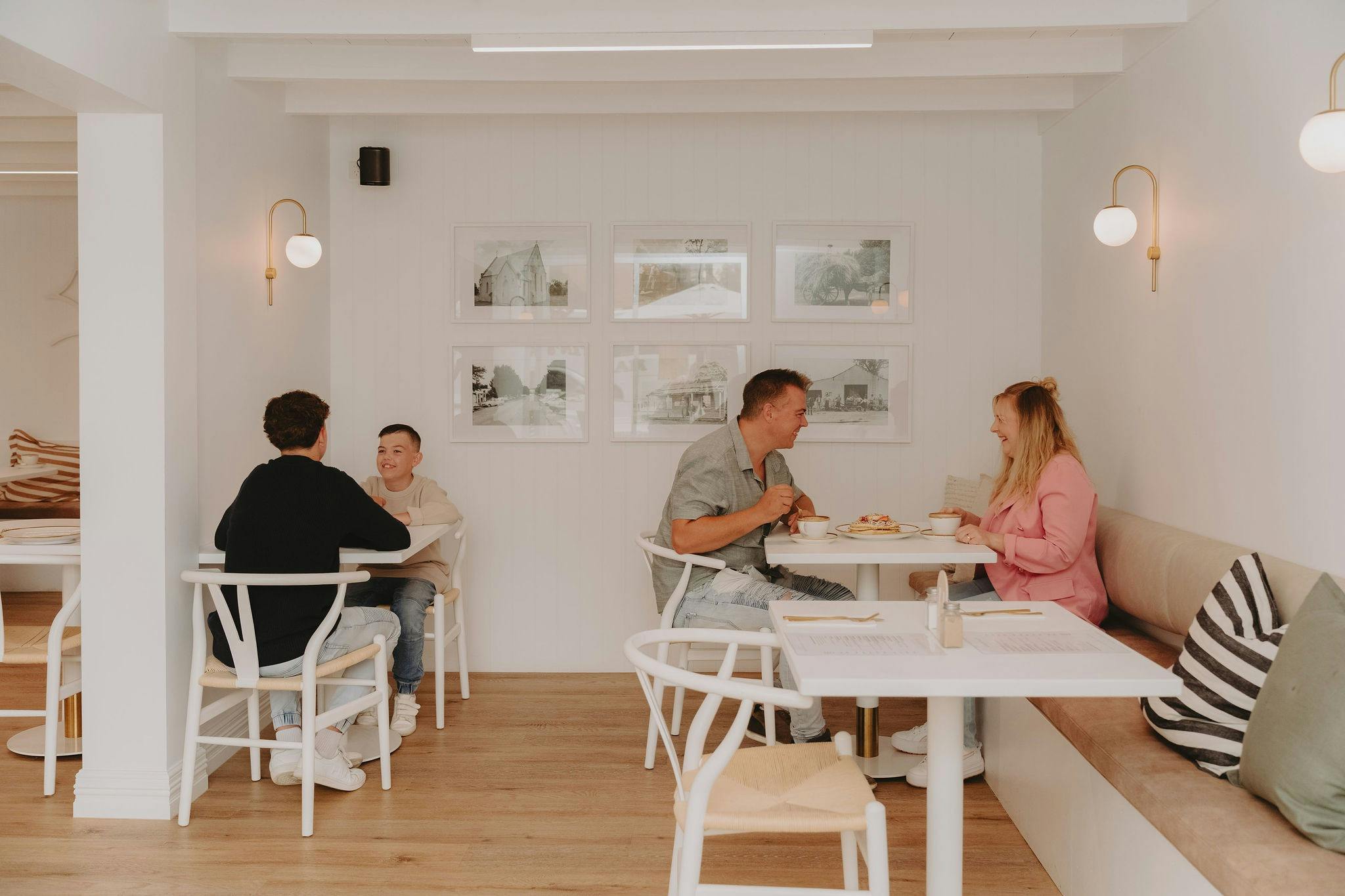 A couple and two boys sitting on separate tables drinking coffee
