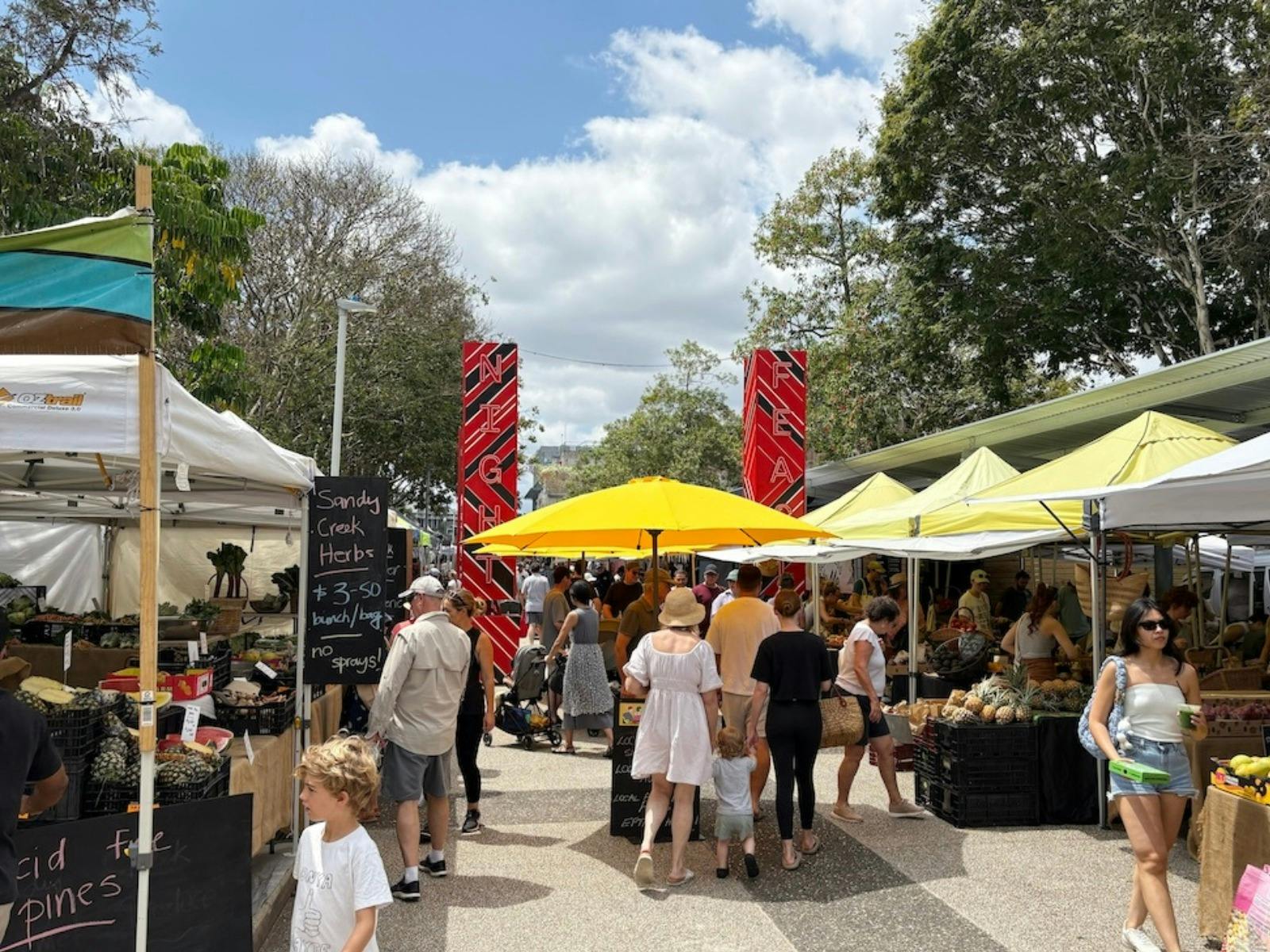 Entrance to the Jan Powers Farmers Markets with many bustling people and stalls Entrance to the Jan Powers Farmers Markets with many bustling people and stalls