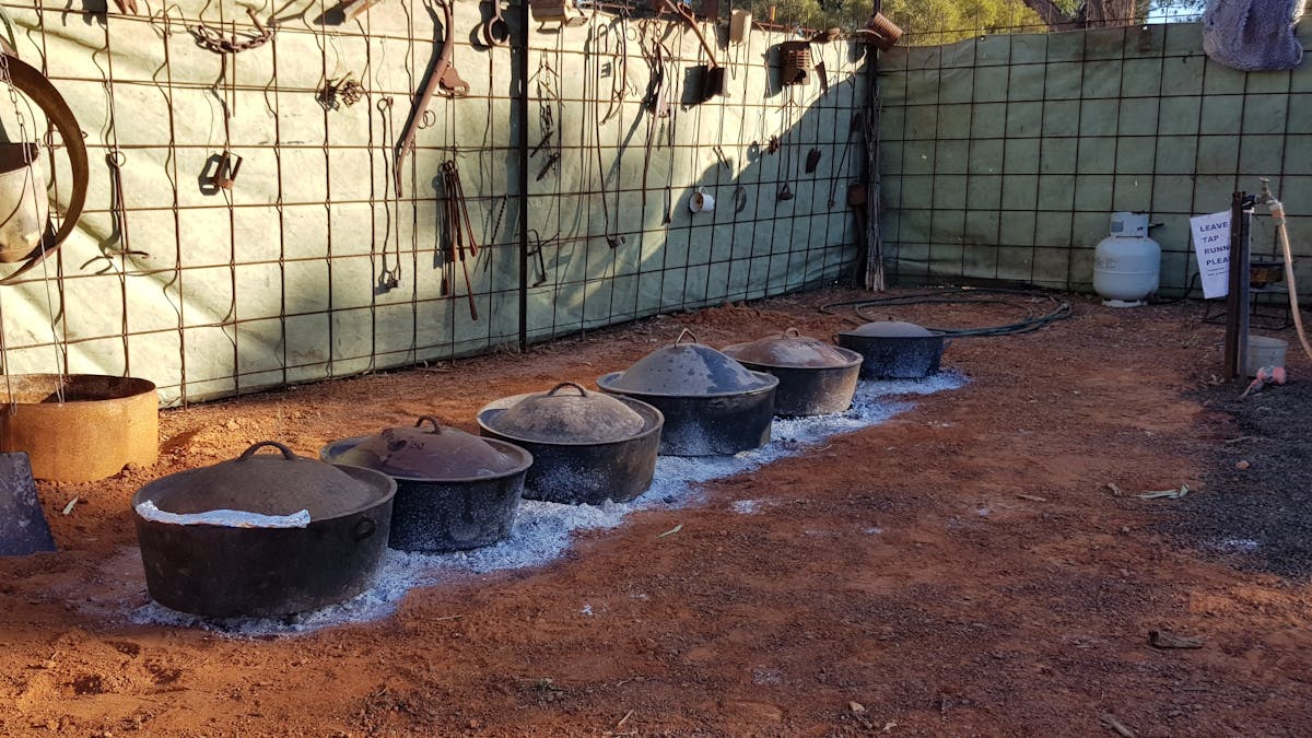 Camp Ovens on hot coals preparing  dinner