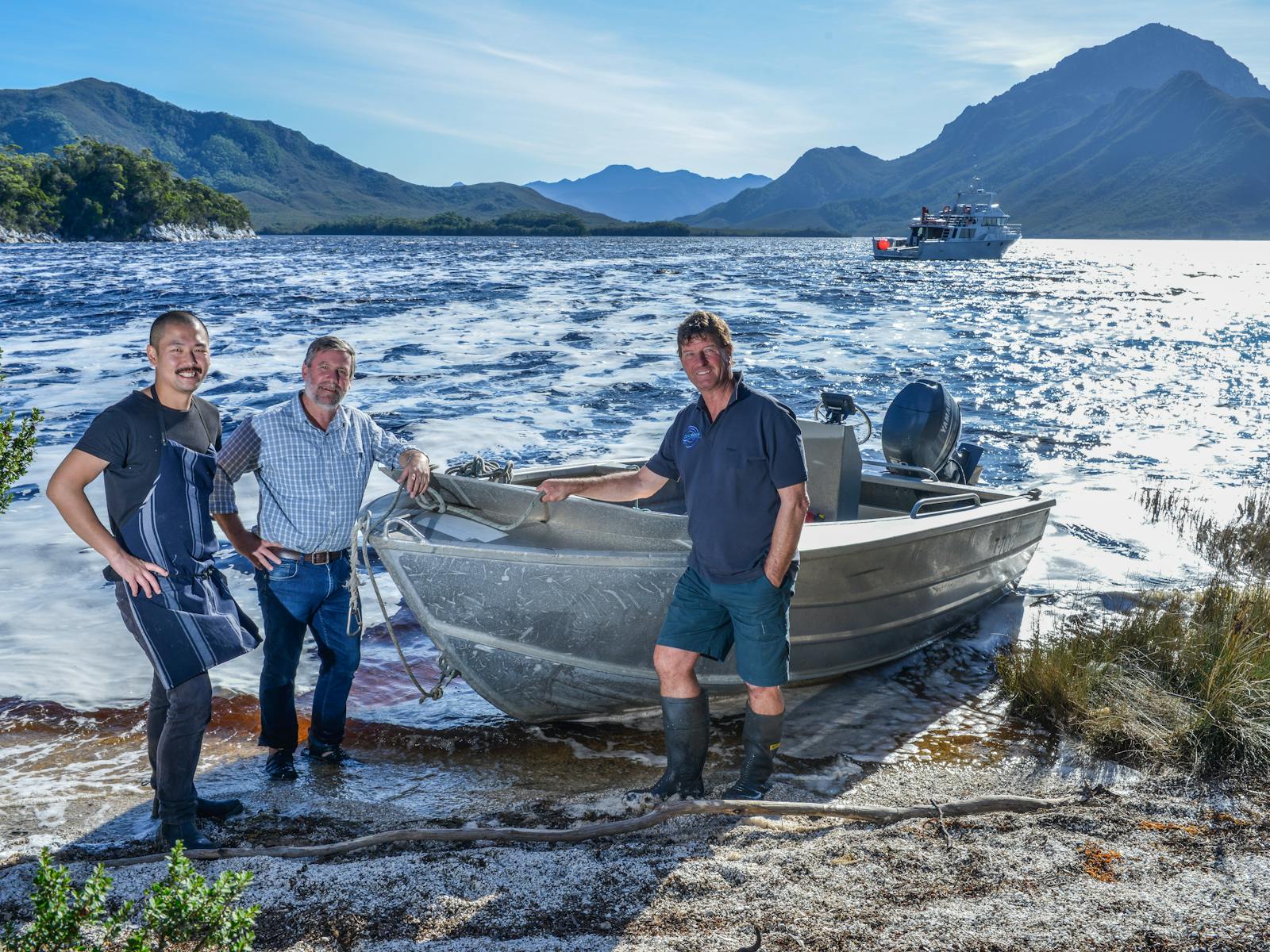 3 crew standing with the tender vessel on the shores of port davey.