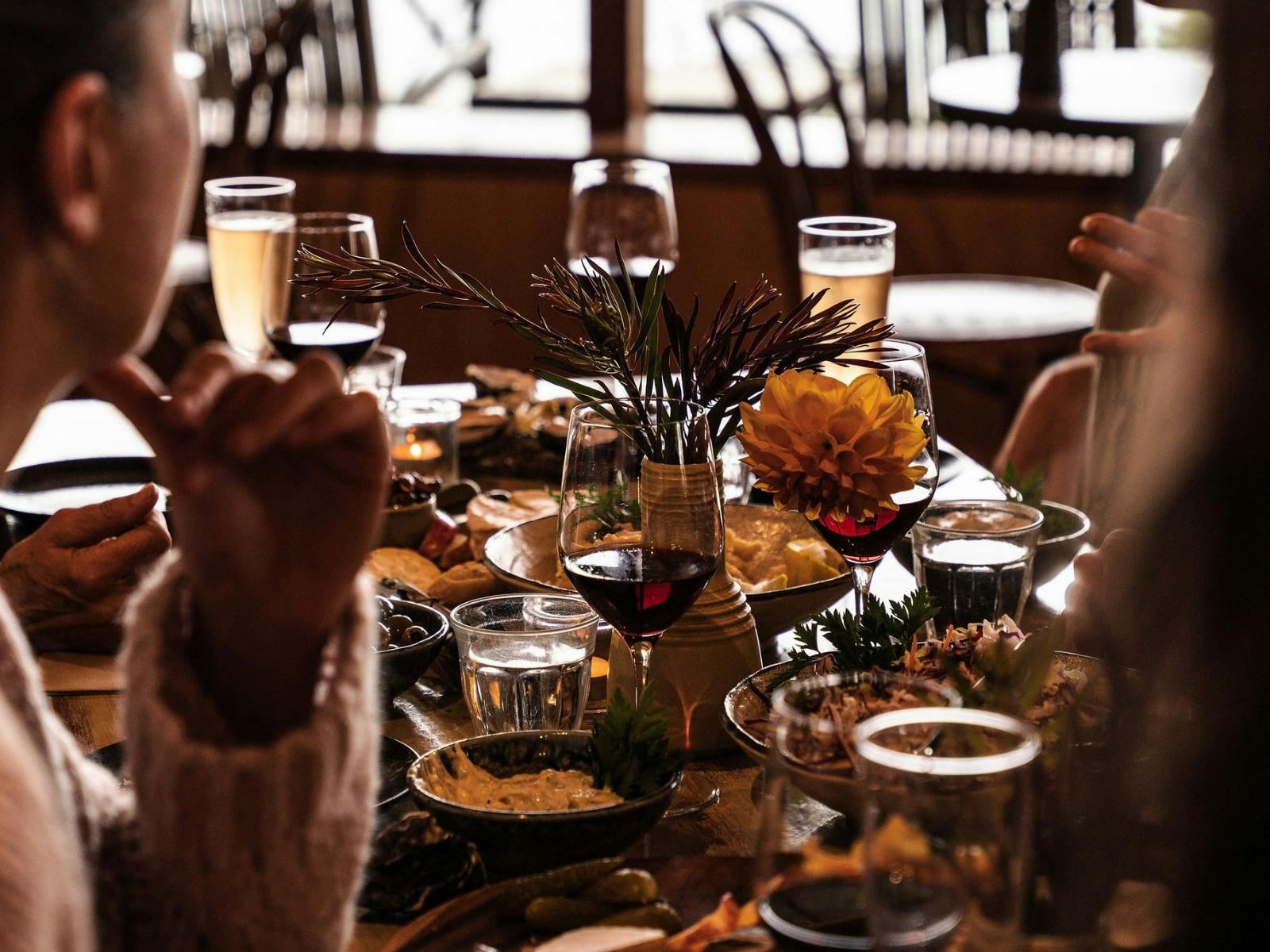 Abundantly set long-table with wine, flowers, and shared plates of food.