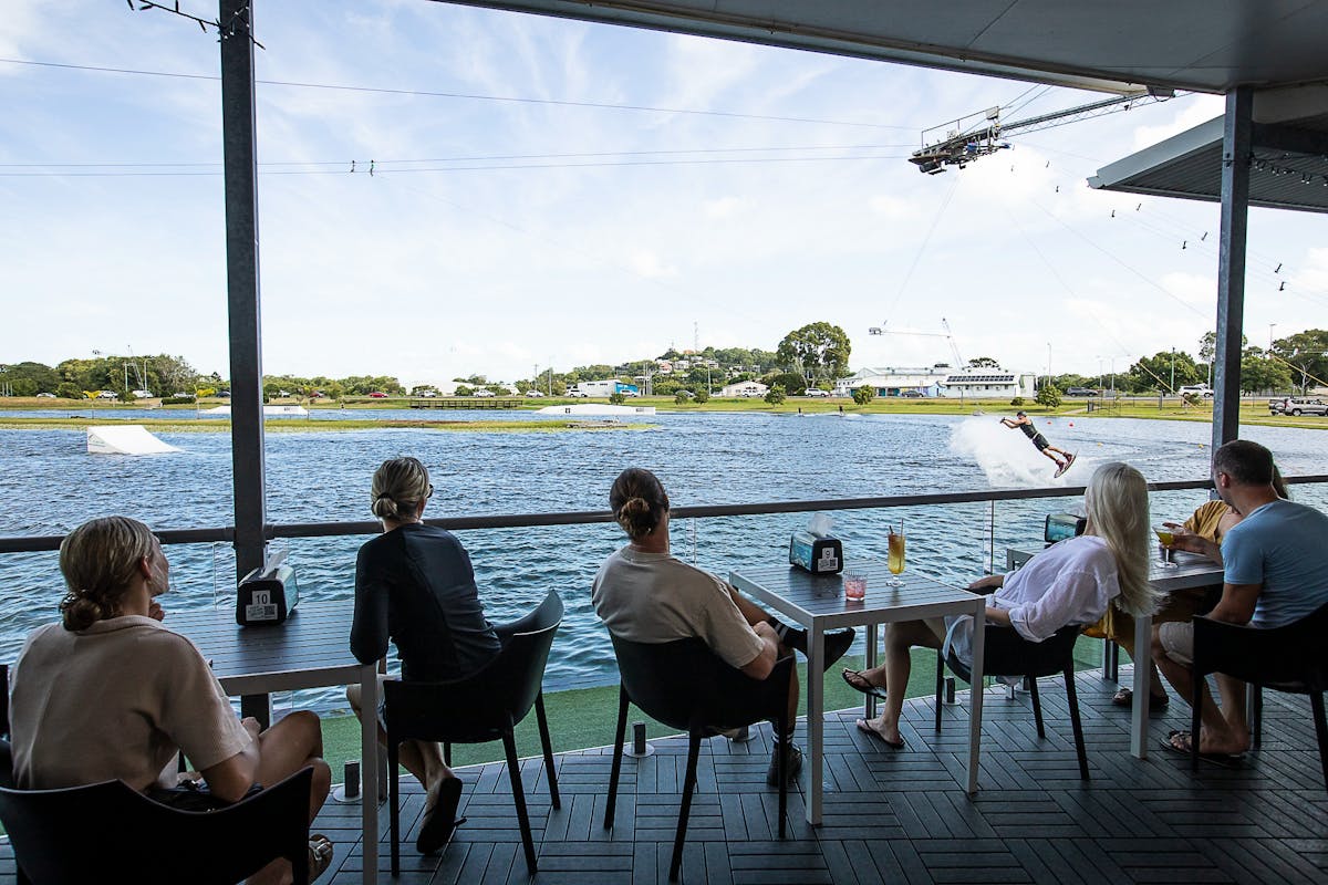 Customers enjoying a drink, relaxing,  watching the wakeboarding lake from the cafe deck.