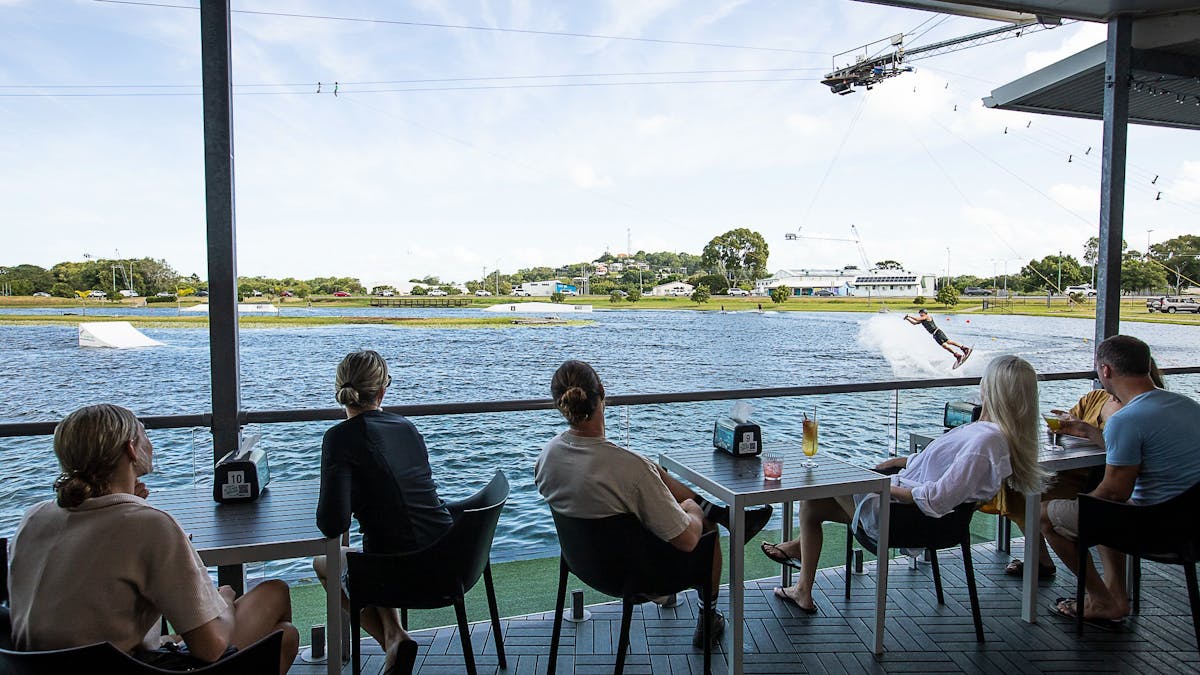 Customers enjoying a drink, relaxing,  watching the wakeboarding lake from the cafe deck.
