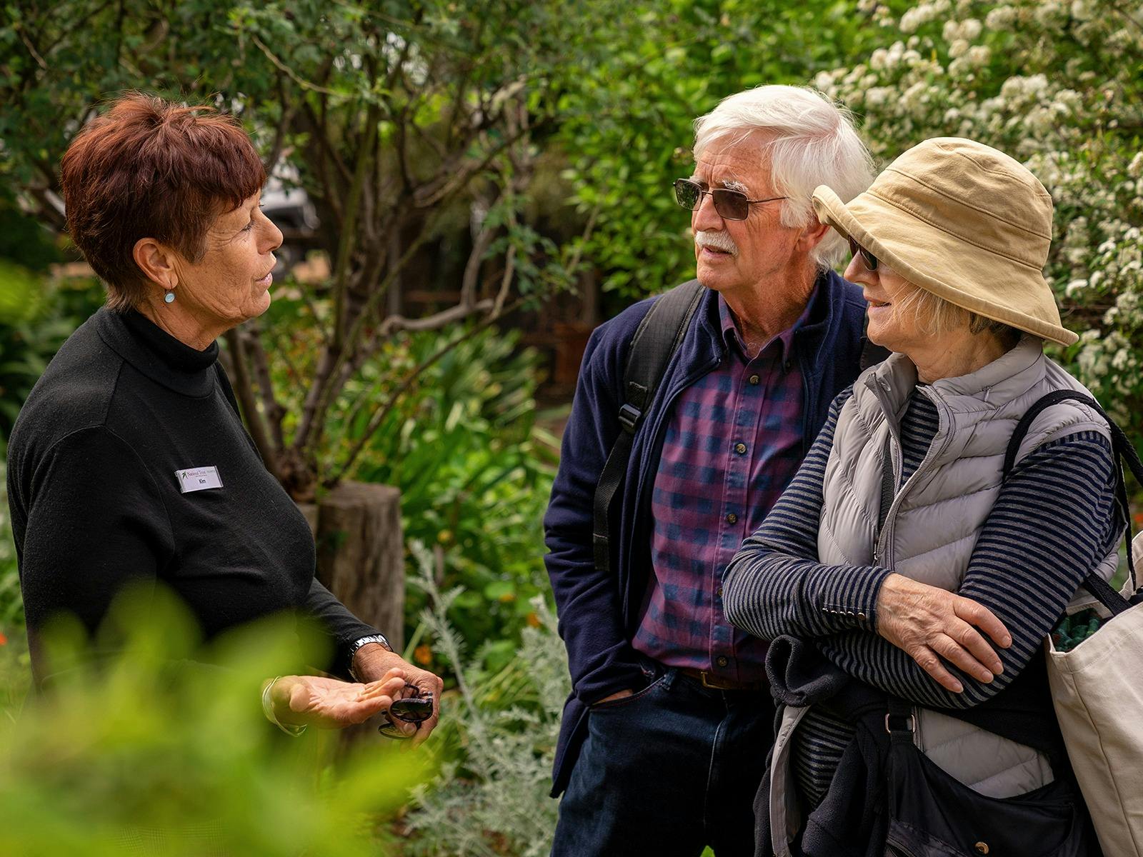 A woman talking to a man and a women in the garden