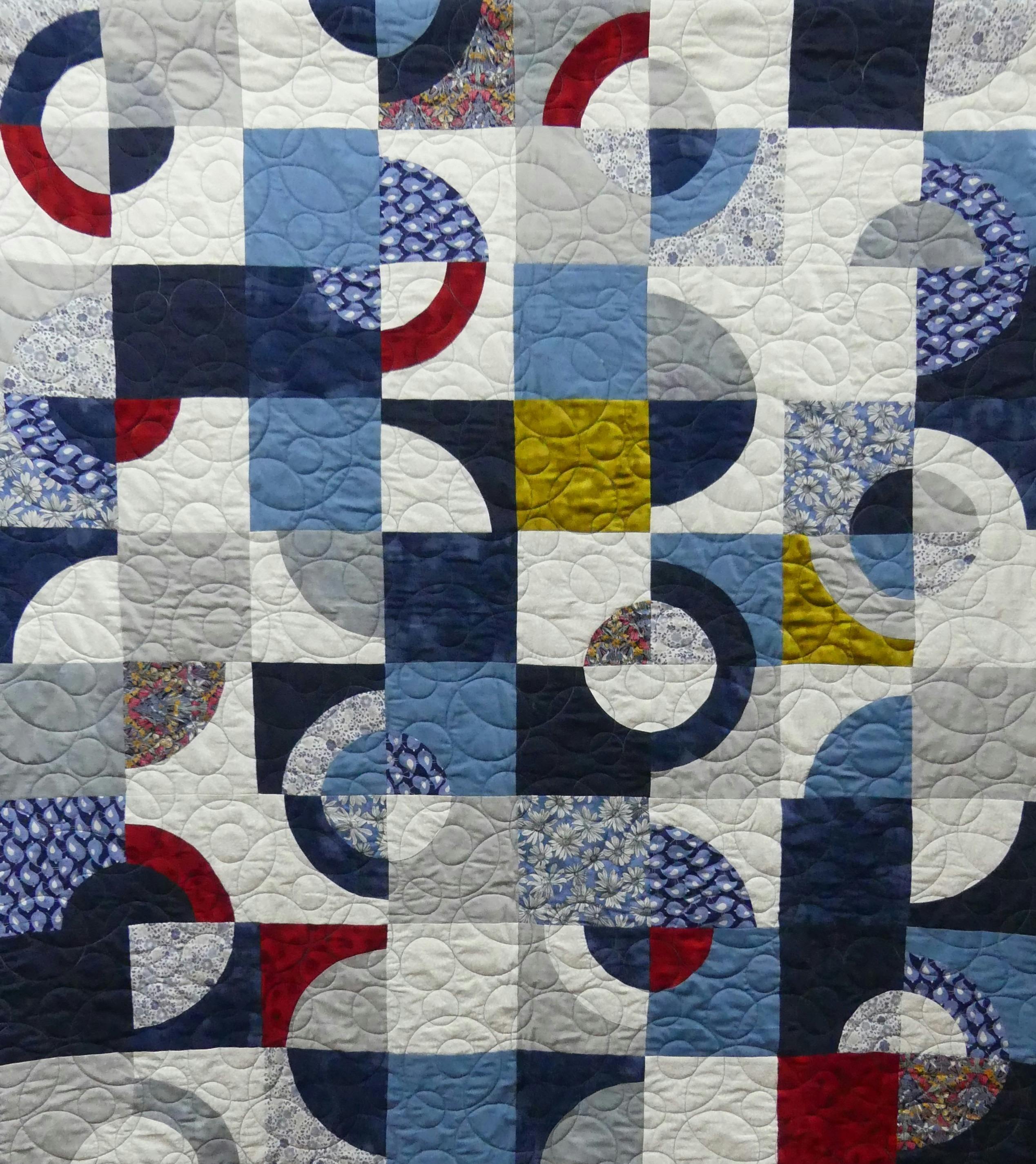 Drunkard's Path blocks done in blues, white, grey, burgundy and gold.