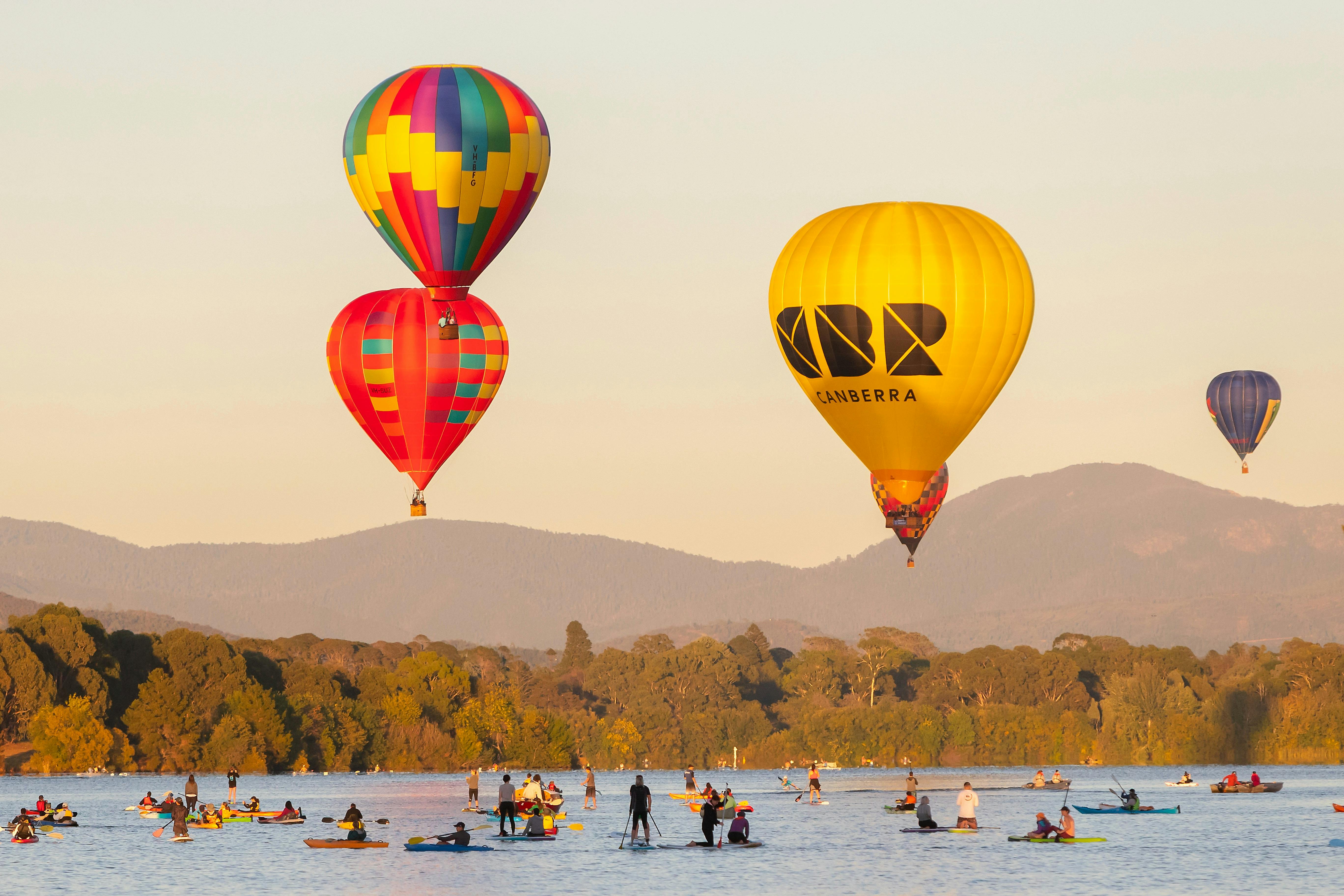 Four floating hot air balloons over lake in Canberra