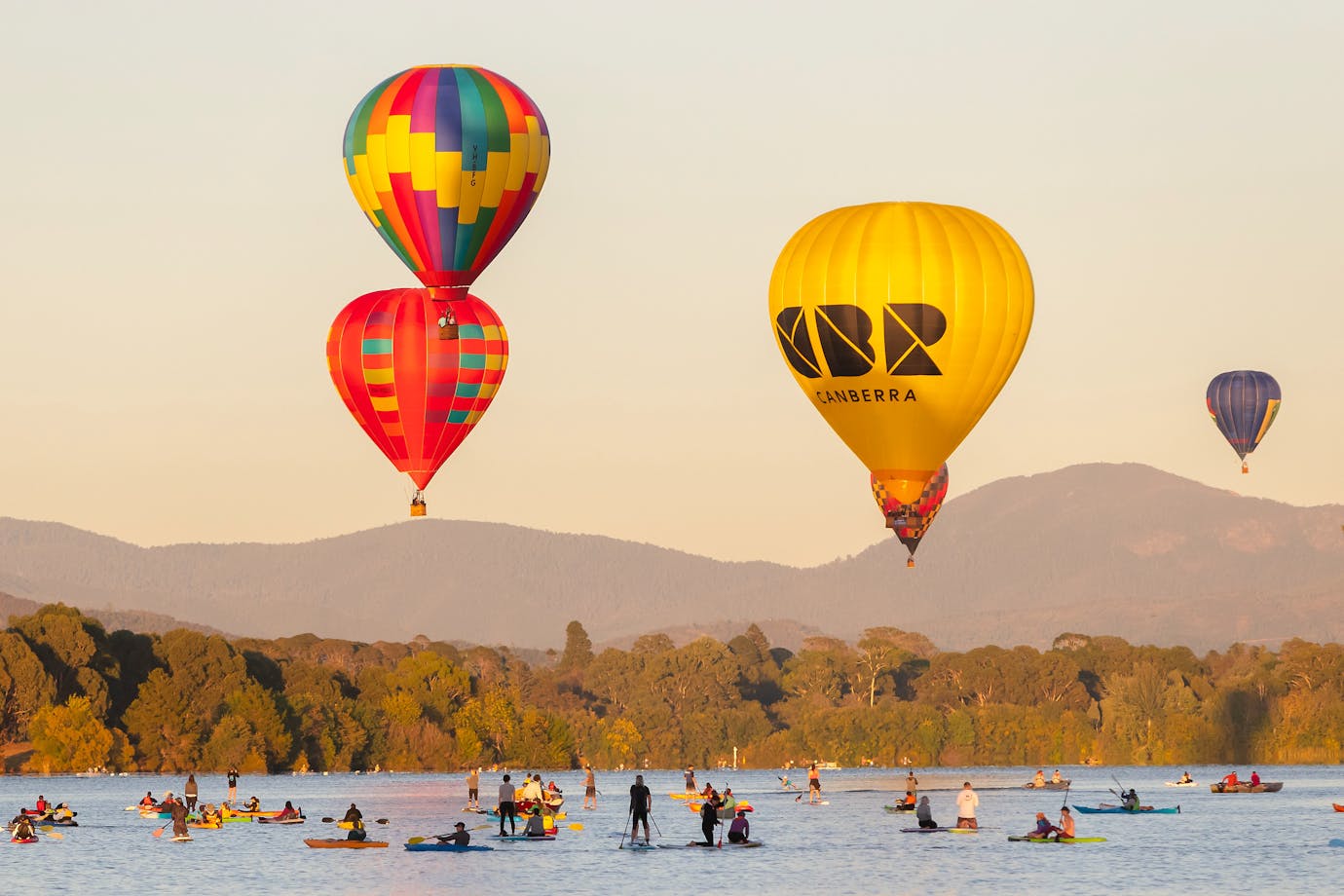 Four floating hot air balloons over lake in Canberra