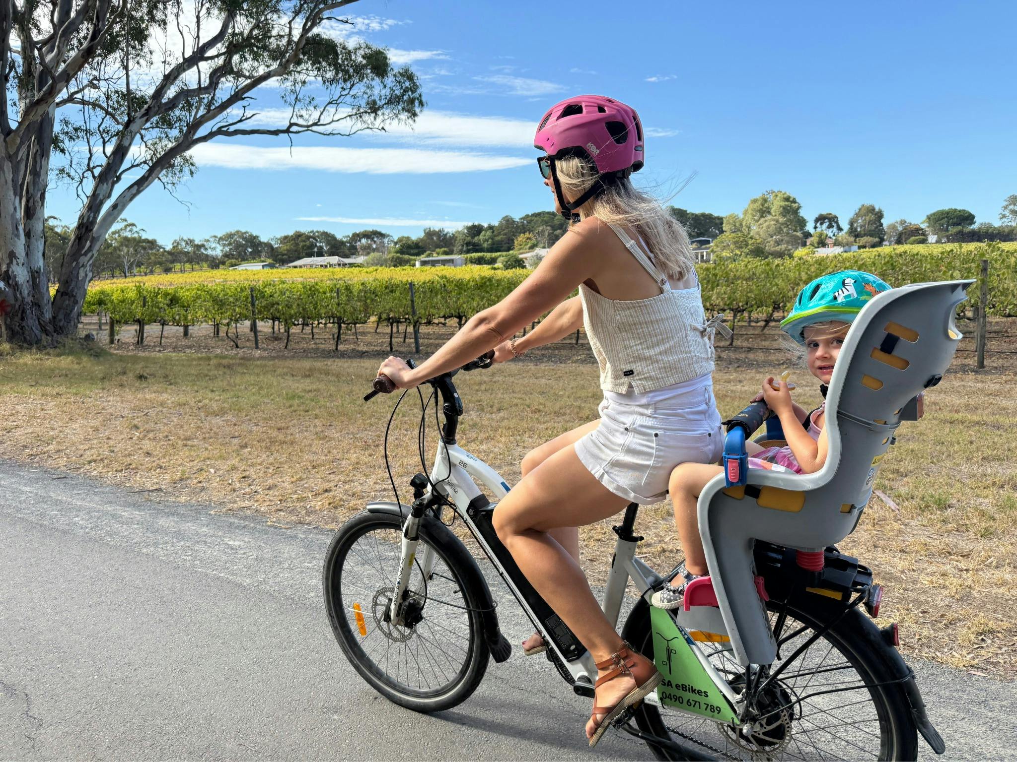A woman riding an ebike along the Shiraz Trail with a young child in the rearmounted childseat