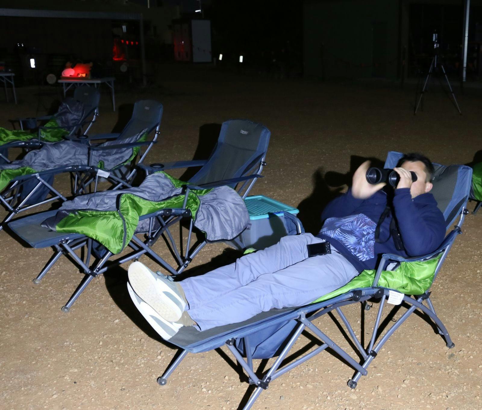Man on top of his sleeping bag while viewing  through binoculars