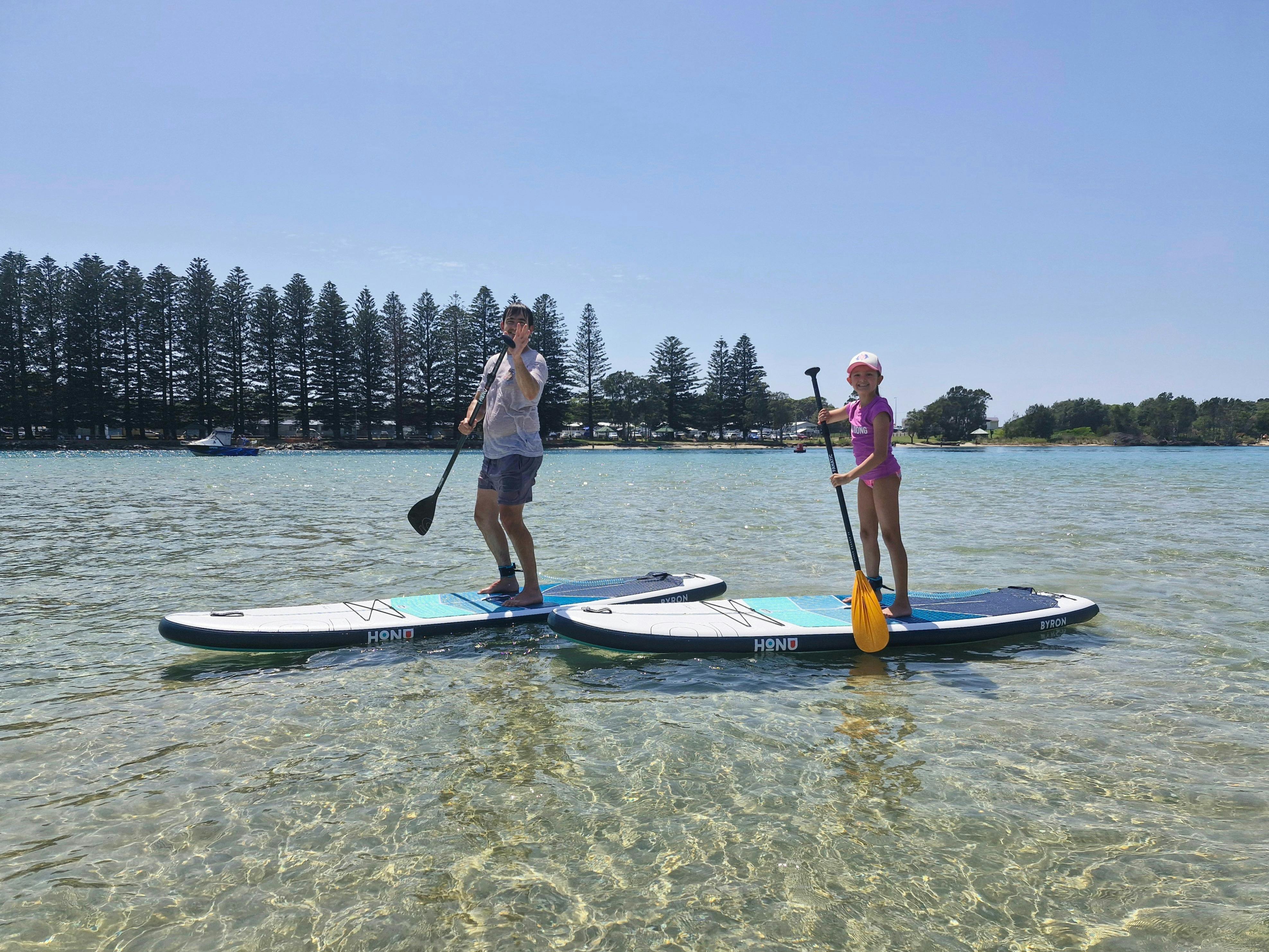 A father and daughtering enjoying paddle boarding on a calm lake