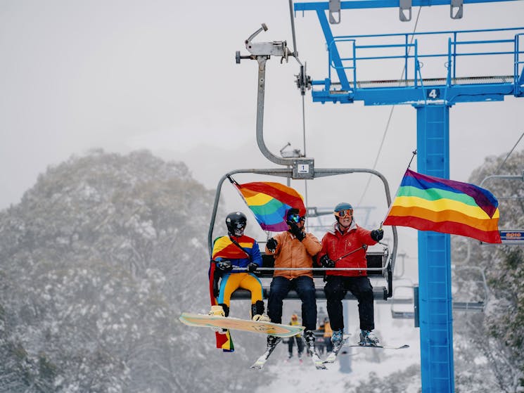 3 ski week participants on the chairlift with rainbow flags