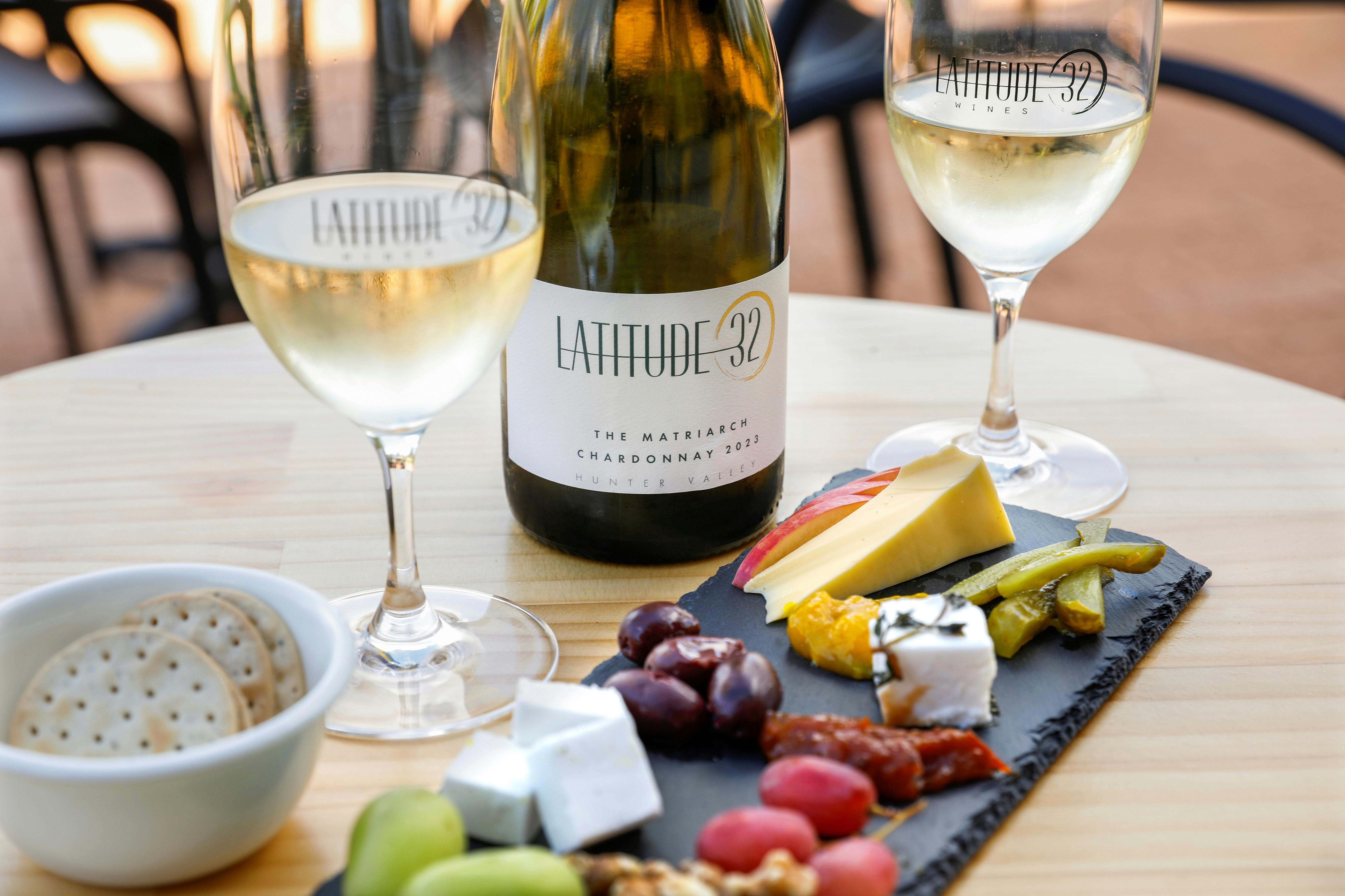 cheese plate, bottle of matriarch chardonnay and two full wine glasses