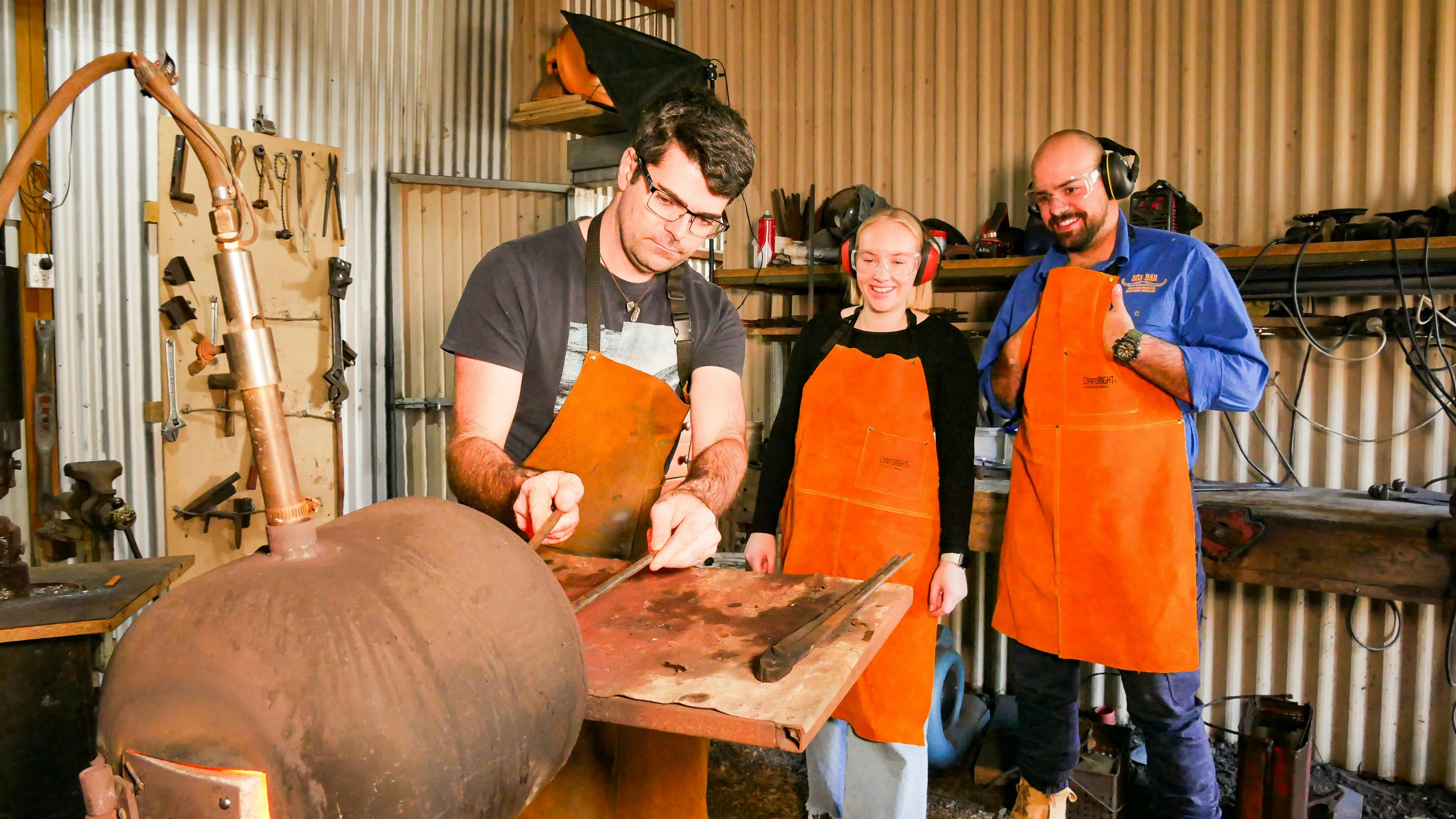 Tom guiding a couple through the first step heating metal in the gas forge
