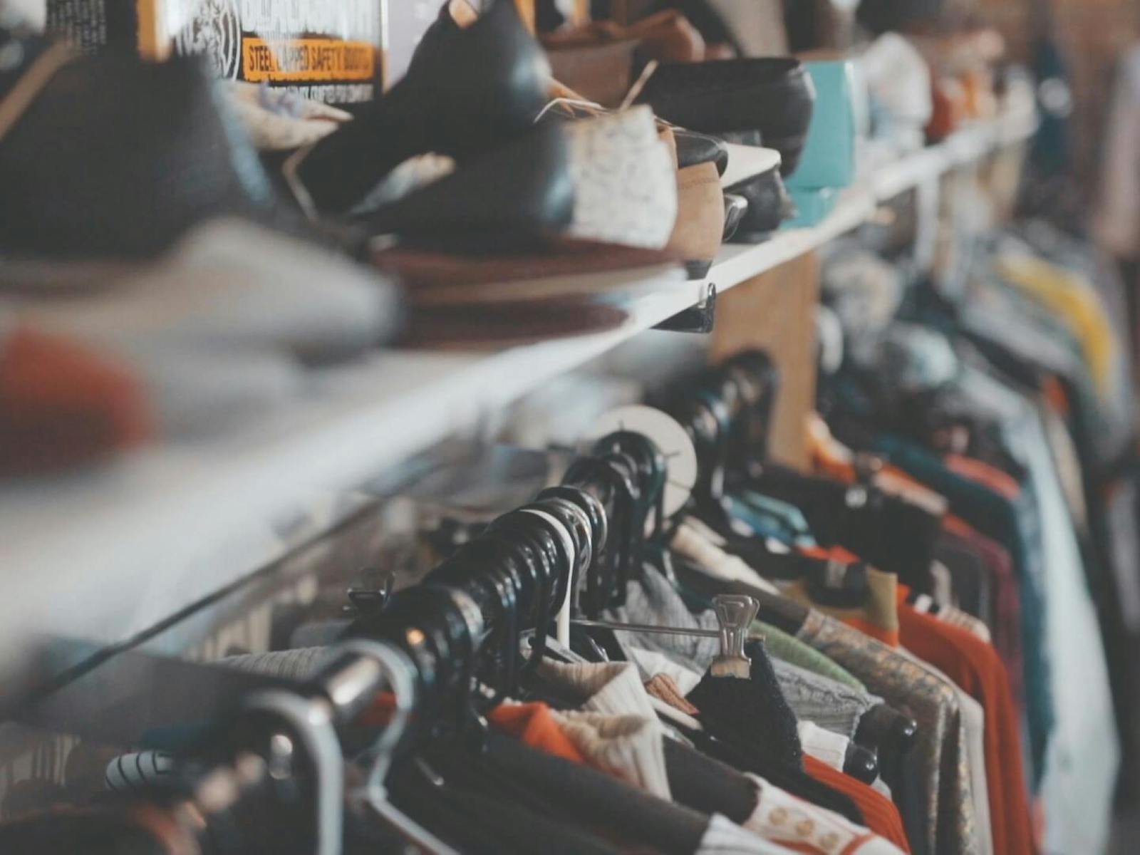 Image of a clothing rack with a line of shoes on top