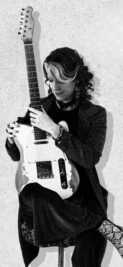 A lady sitting holding a guitar