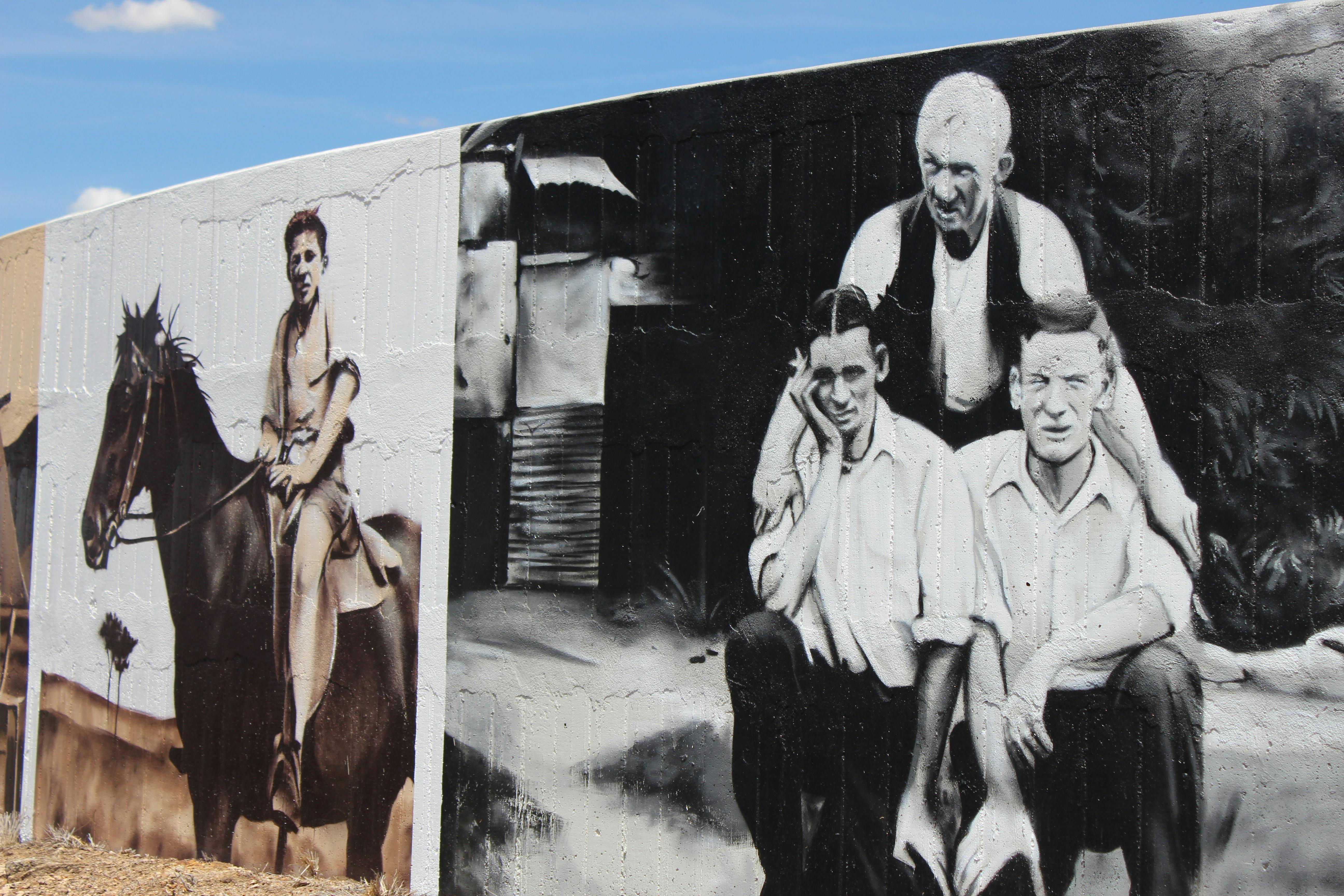 Auf der einen Seite ein Reiter auf einem Pferd, auf der anderen ein Vater mit zwei Söhnen, in Schwarzweiß.