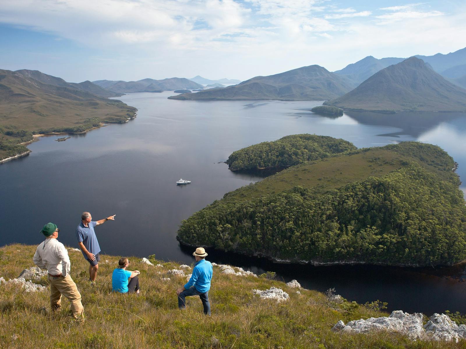 4 People looking at a view after hiking to a point looking over Port Davey and our vessel, Odalisque